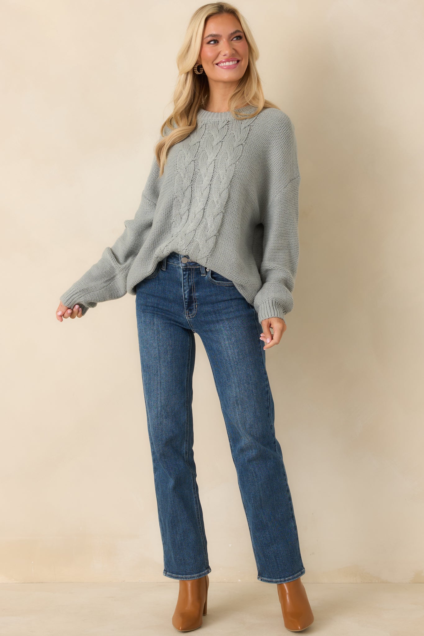 Stone blue sweater highlighting the classic cable design, long sleeves, and clean round collar.