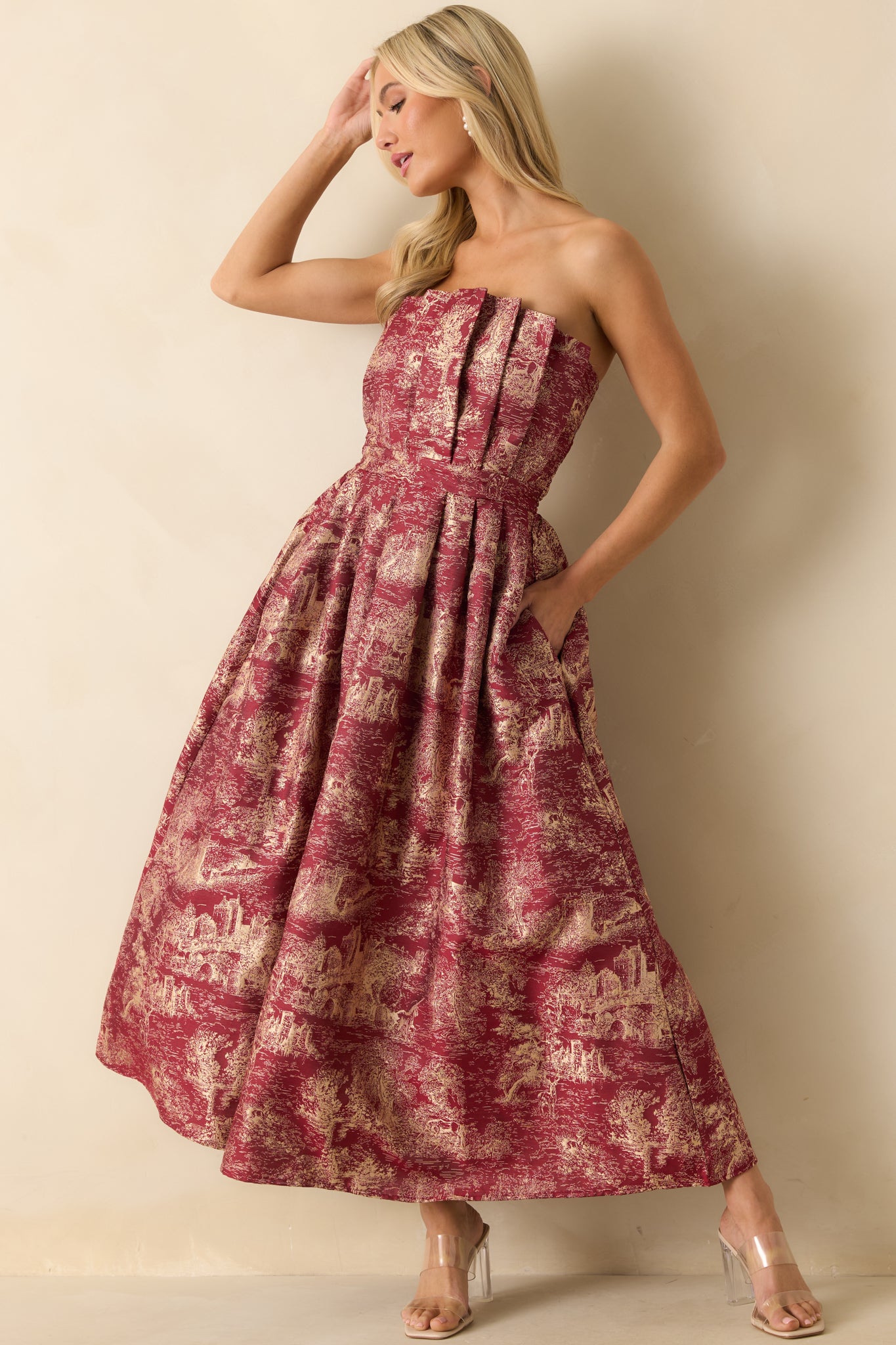 Strapless burgundy dress showcasing a detailed ivory jacquard design, fitted pleated bodice, and full A-line silhouette.