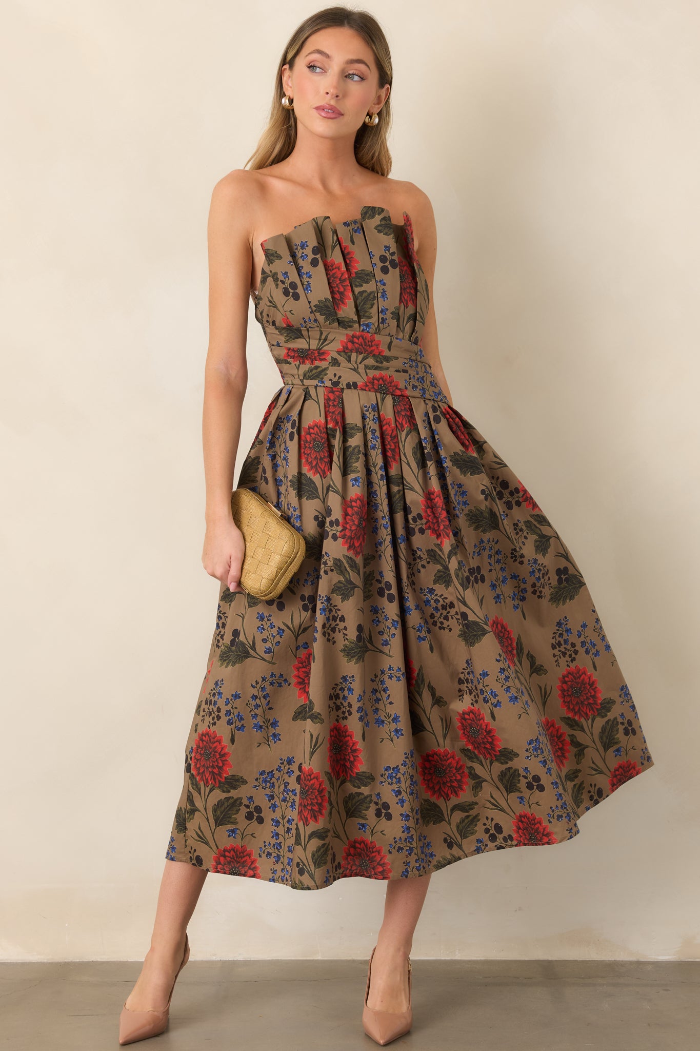 Strapless cotton midi dress featuring a pleated bodice, defined waist, and full skirt covered in red blooms, cobalt florals, and deep olive greenery.