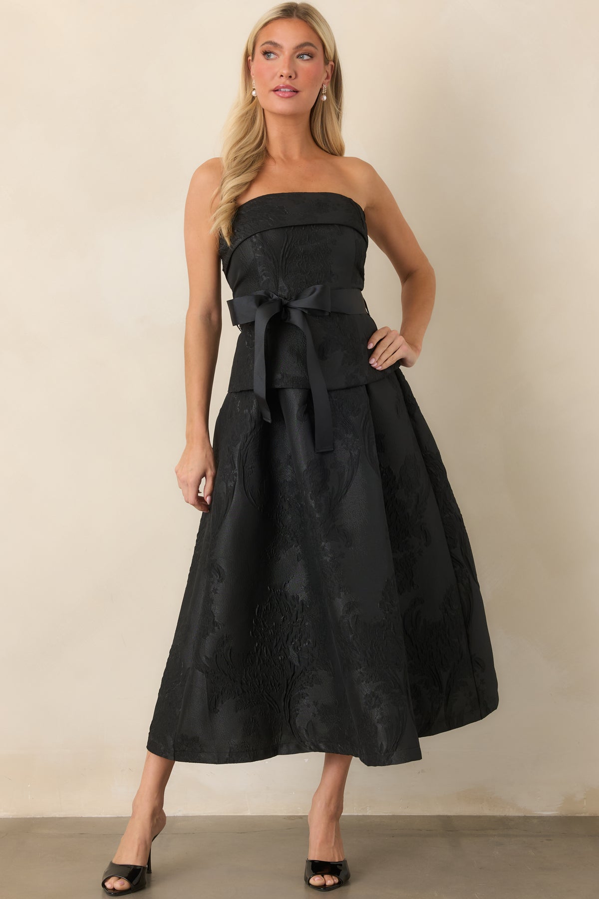 Strapless dress showcasing corset-inspired seaming, a wide grosgrain sash, and split peplum waist overlay.
