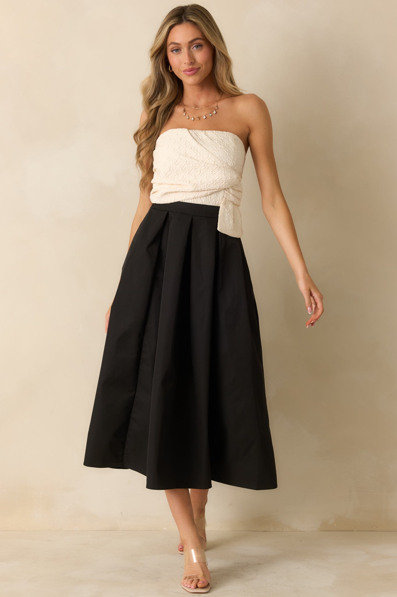 Two-tone strapless dress with a structured ivory bodice, high-waisted design, and flowing A-line skirt in black.