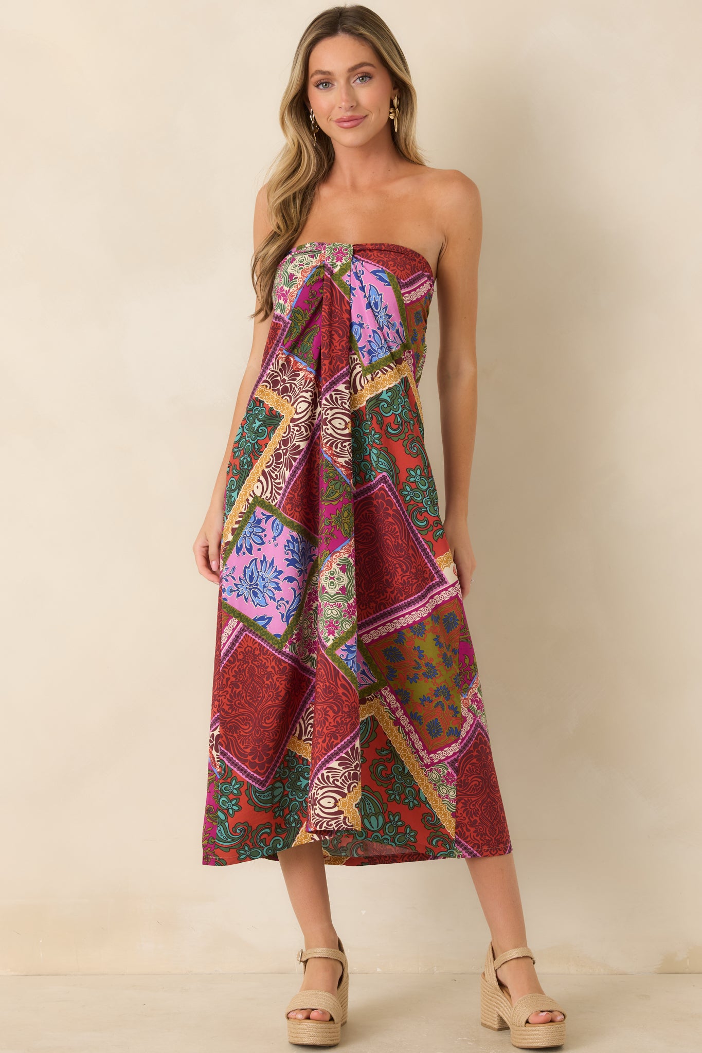 Strapless red patchwork midi dress designed with a flowing fit, front box pleat, and vibrant mixed-print pattern.