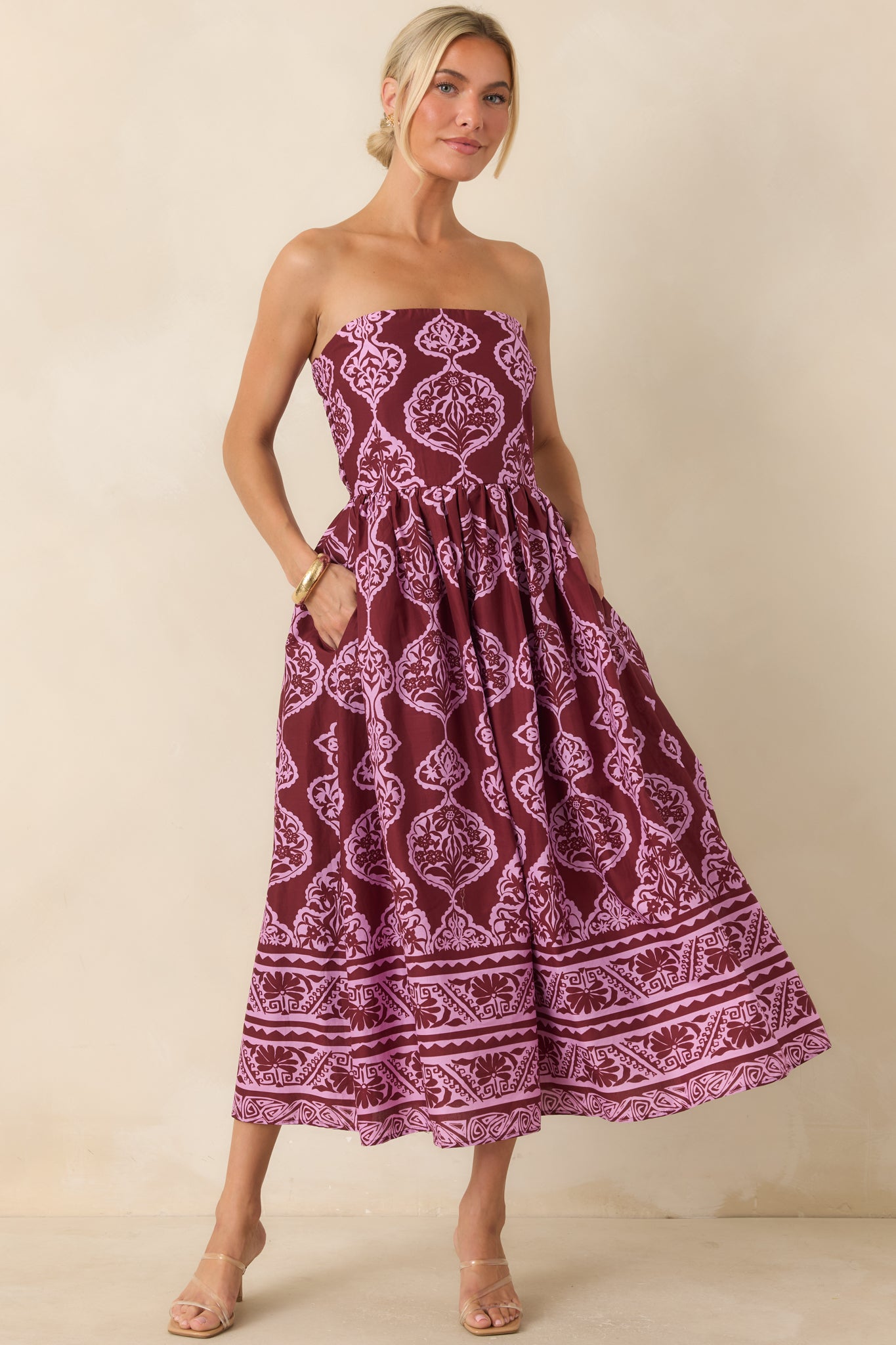 Strapless wine and orchid pink midi dress featuring a fitted bodice, medallion print, gathered skirt, and decorative border hem.