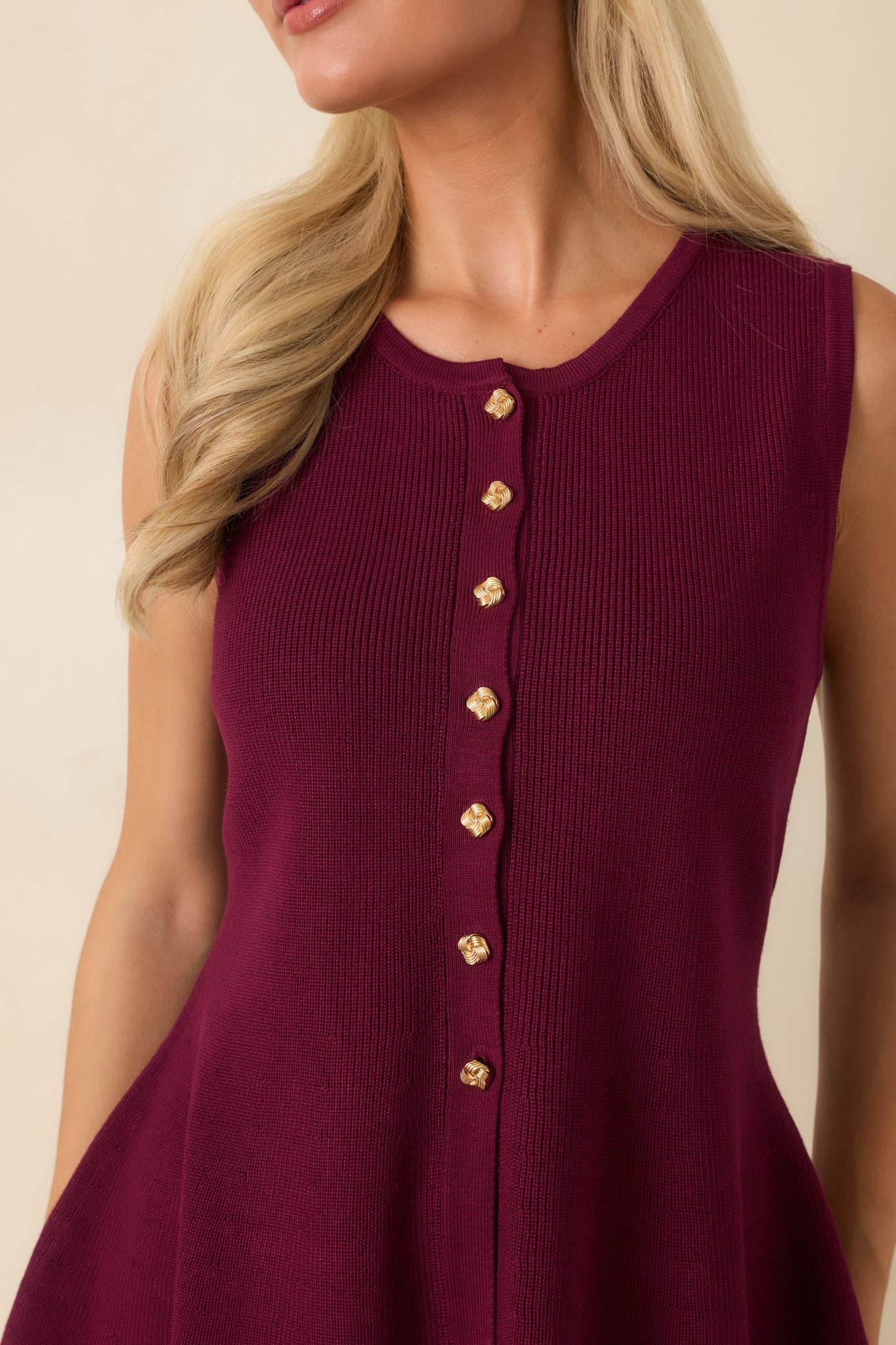 Close-up of the stretch knit fabric displaying the gold-tone buttons and finely finished peplum construction.