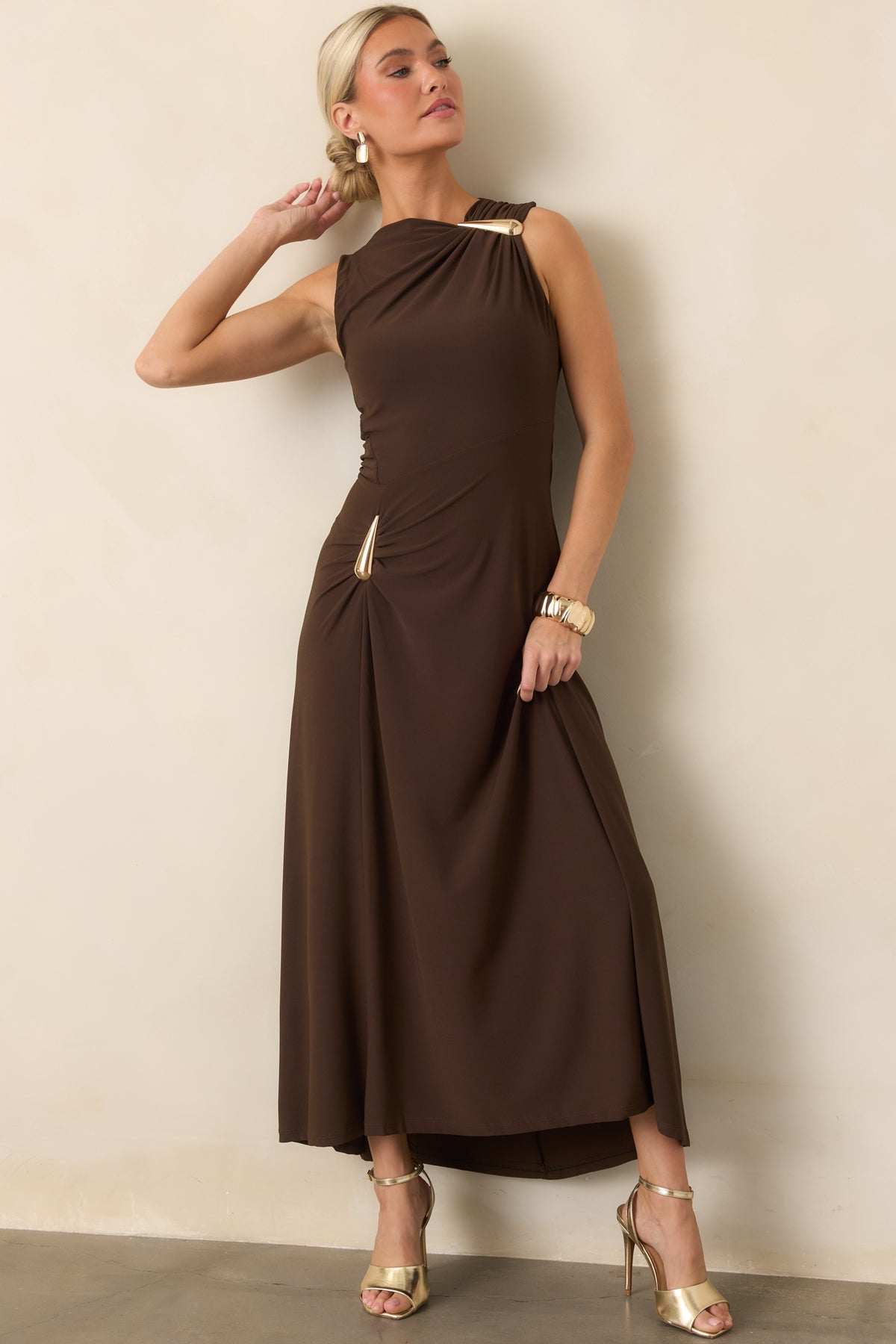 Stretchy maxi dress showcasing the sculptural gold-tone hardware, fitted bodice, and softly flared skirt.