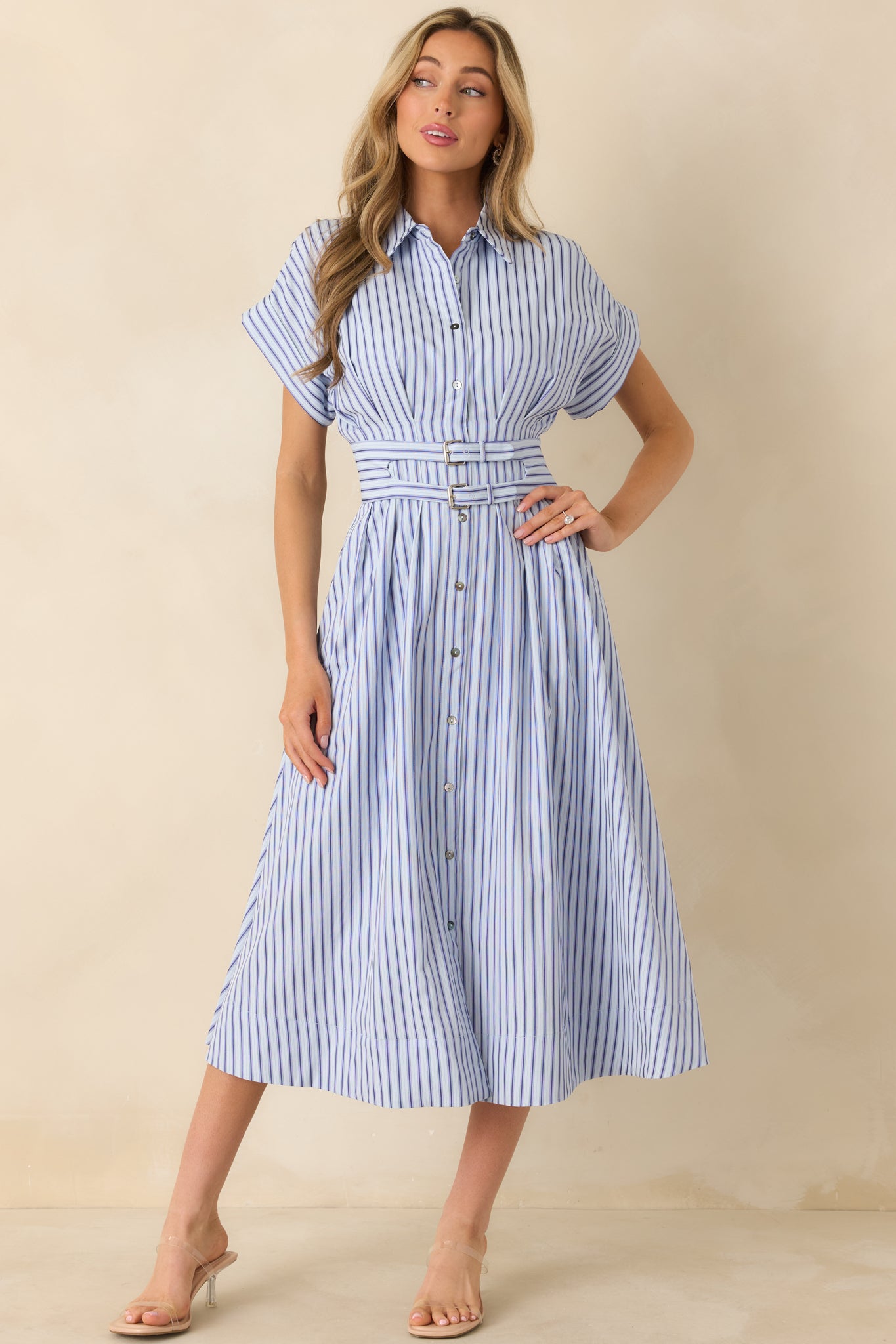 Striped blue midi dress with a structured collar, button-front closure, side pockets, and gentle skirt pleating for movement.