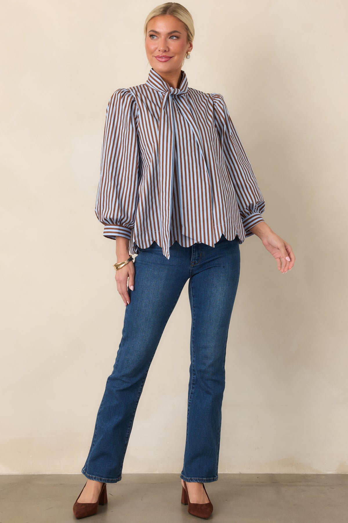 Striped button-front blouse featuring a softly tied neckline, voluminous sleeves, and a feminine scalloped hem.