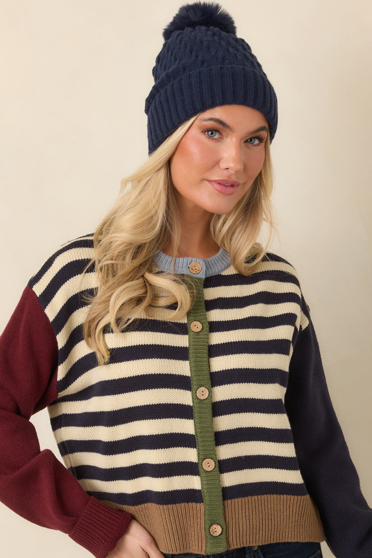 Olive button placket with neutral buttons contrasts against the striped knit cardigan front.