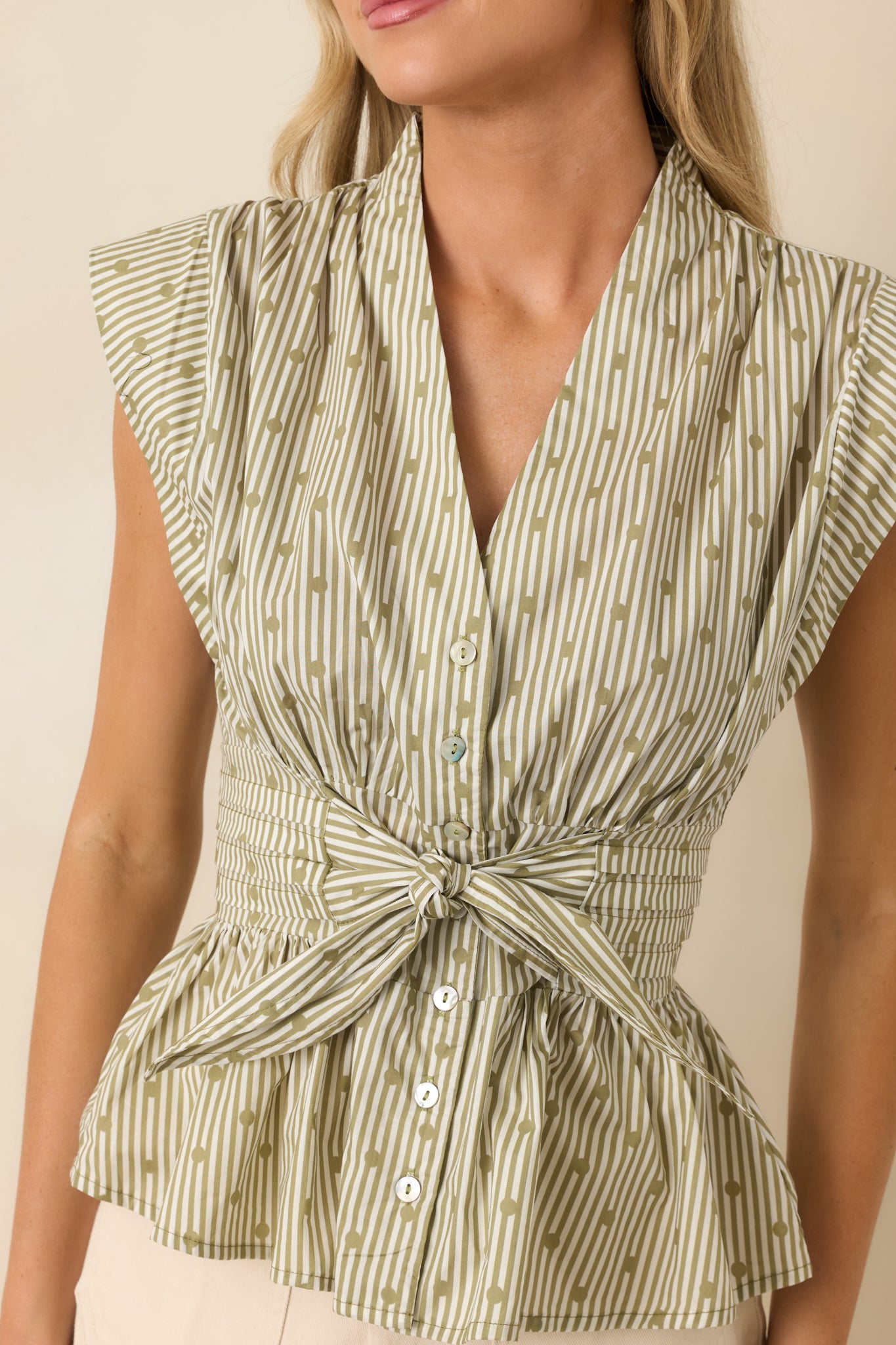 Close-up of the striped cotton blouse highlighting the button-front closure, tie waist, and textured woven fabric.