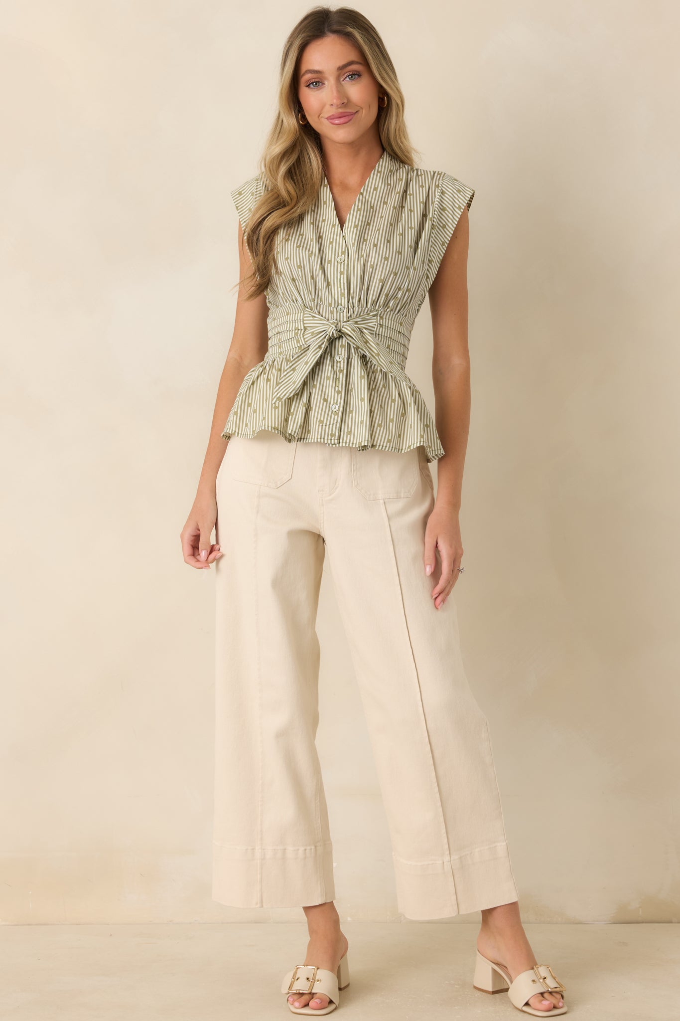 Striped cotton blouse featuring an open V-neckline, cap sleeves, a button-front closure, and a tie waist with a peplum hem.
