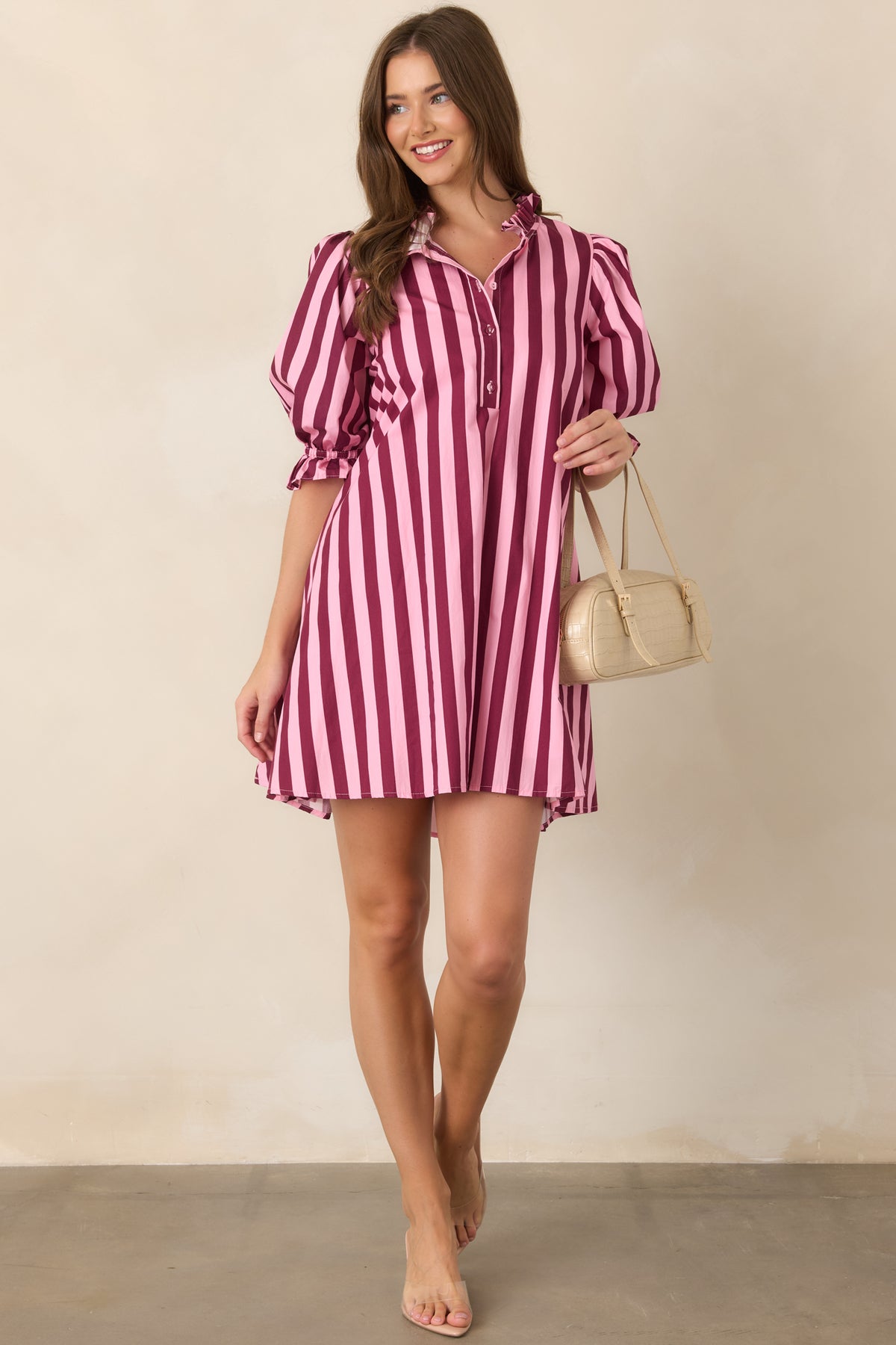 Relaxed striped mini dress designed with a ruffled mock neckline, partial button placket, generously gathered puff sleeves, and a softly shaped waist.