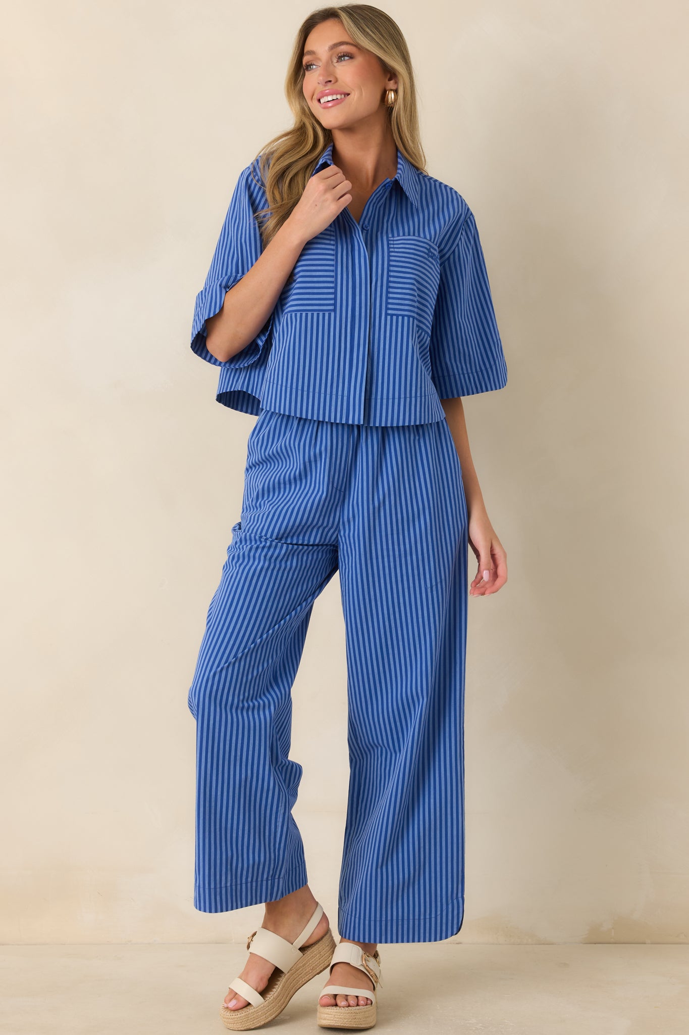 Striped cropped top featuring a collared neckline, elbow-length sleeves, drop shoulder design, and front patch pocket detail.