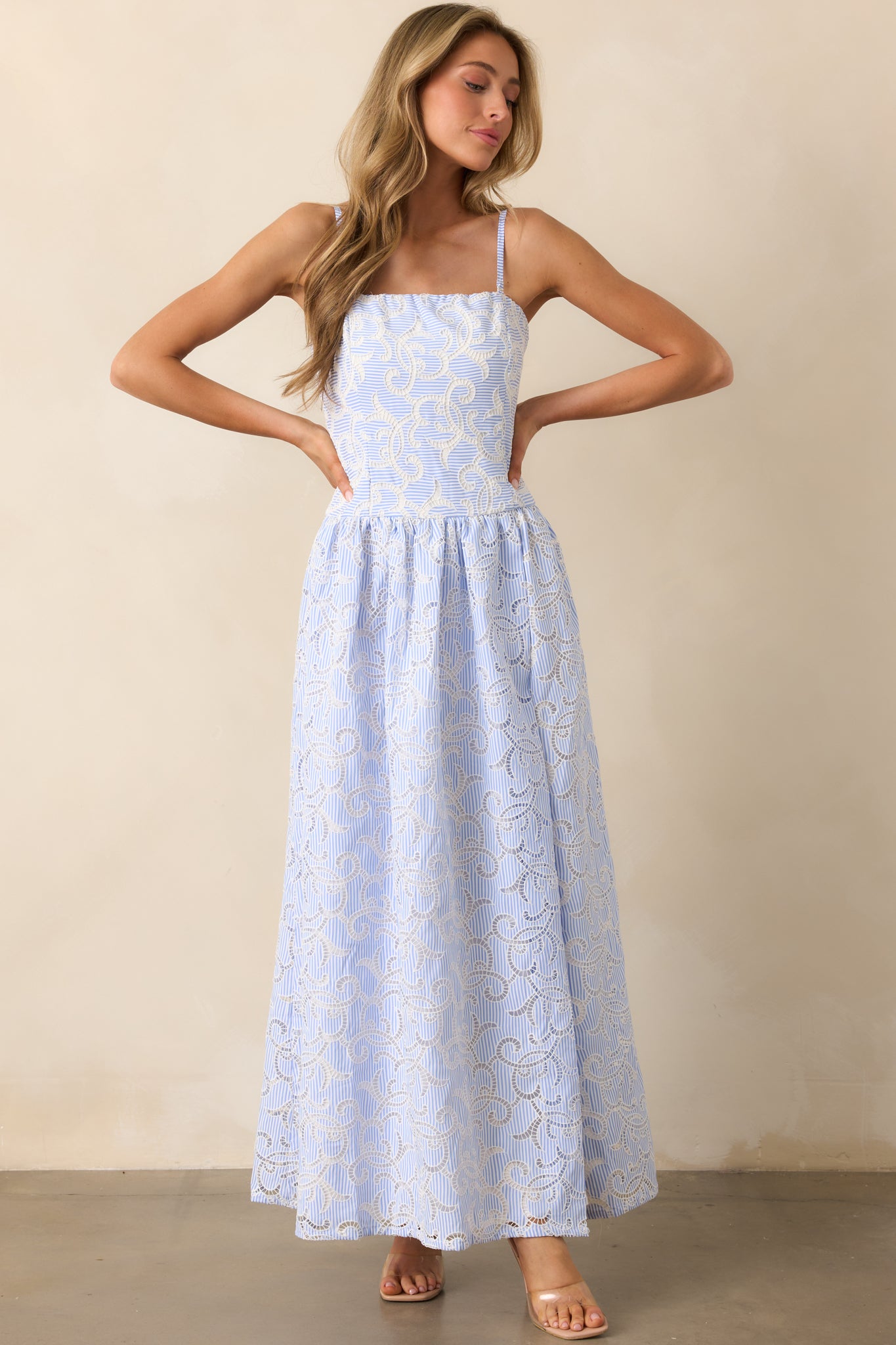 A striped maxi dress, highlighting the embroidered eyelet fabric, white lining, and flowing hem. The delicate pattern adds texture and dimension.