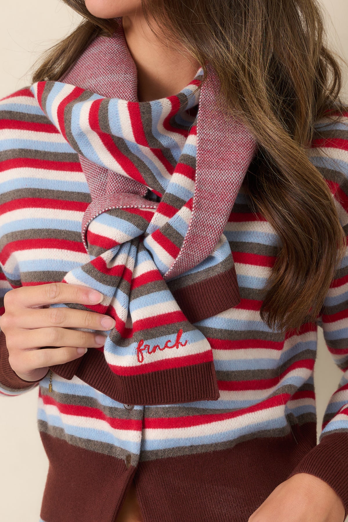 Detailed knit stripes pair with rich brown ribbed trim and button accents on the cardigan front.