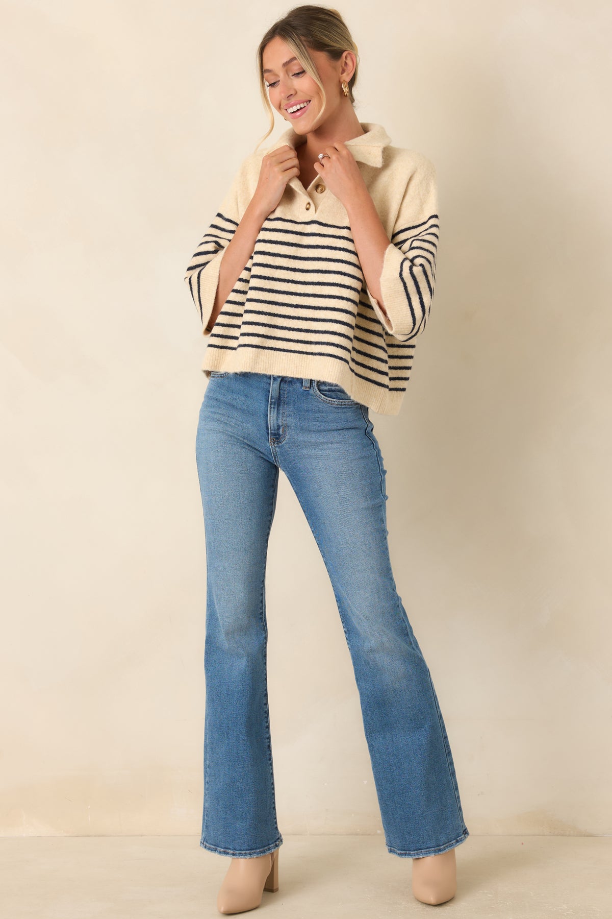 Striped knit top showcasing a partial button placket, wide collar, and slightly cropped hemline.
