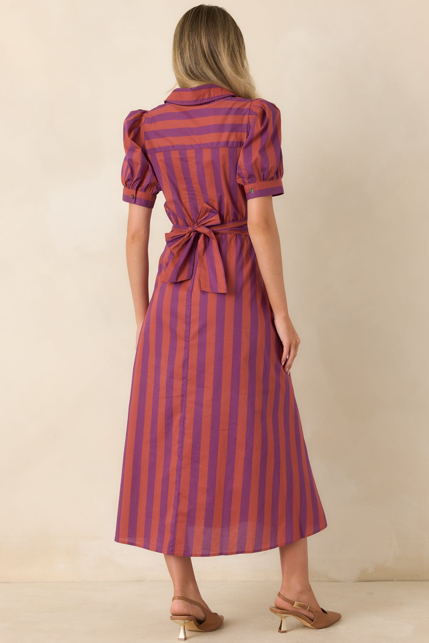 Rear view of the cotton midi dress showcasing the wide wrap-style sash tied at the back, softly gathered full skirt, directional stripe pattern, and short puff sleeves.