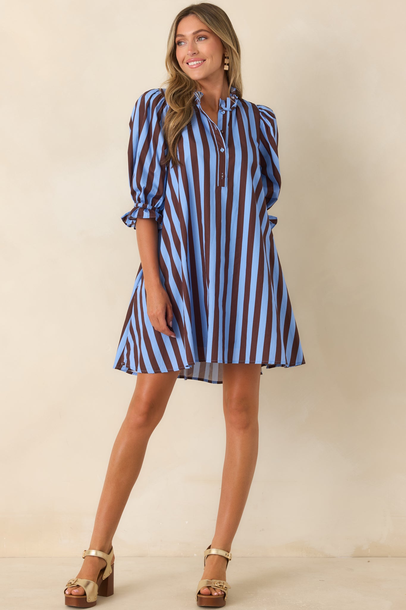 Striped mini dress featuring a ruffled neckline, partial button-front design, and a customizable drawstring waist detail.