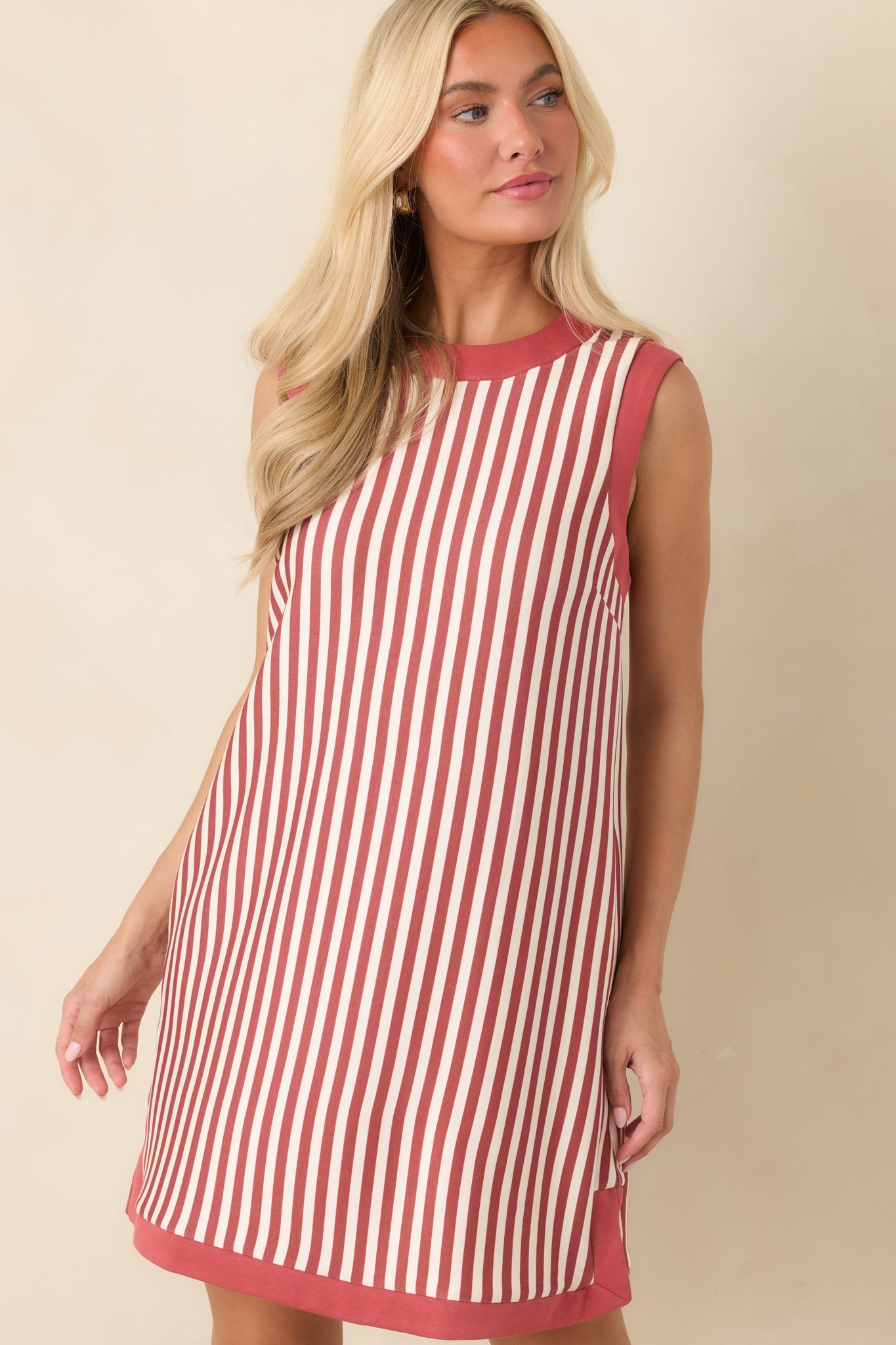 Front detail of the striped mini dress highlighting the round neckline, vertical terracotta and ivory stripes, and contrast terracotta trim.