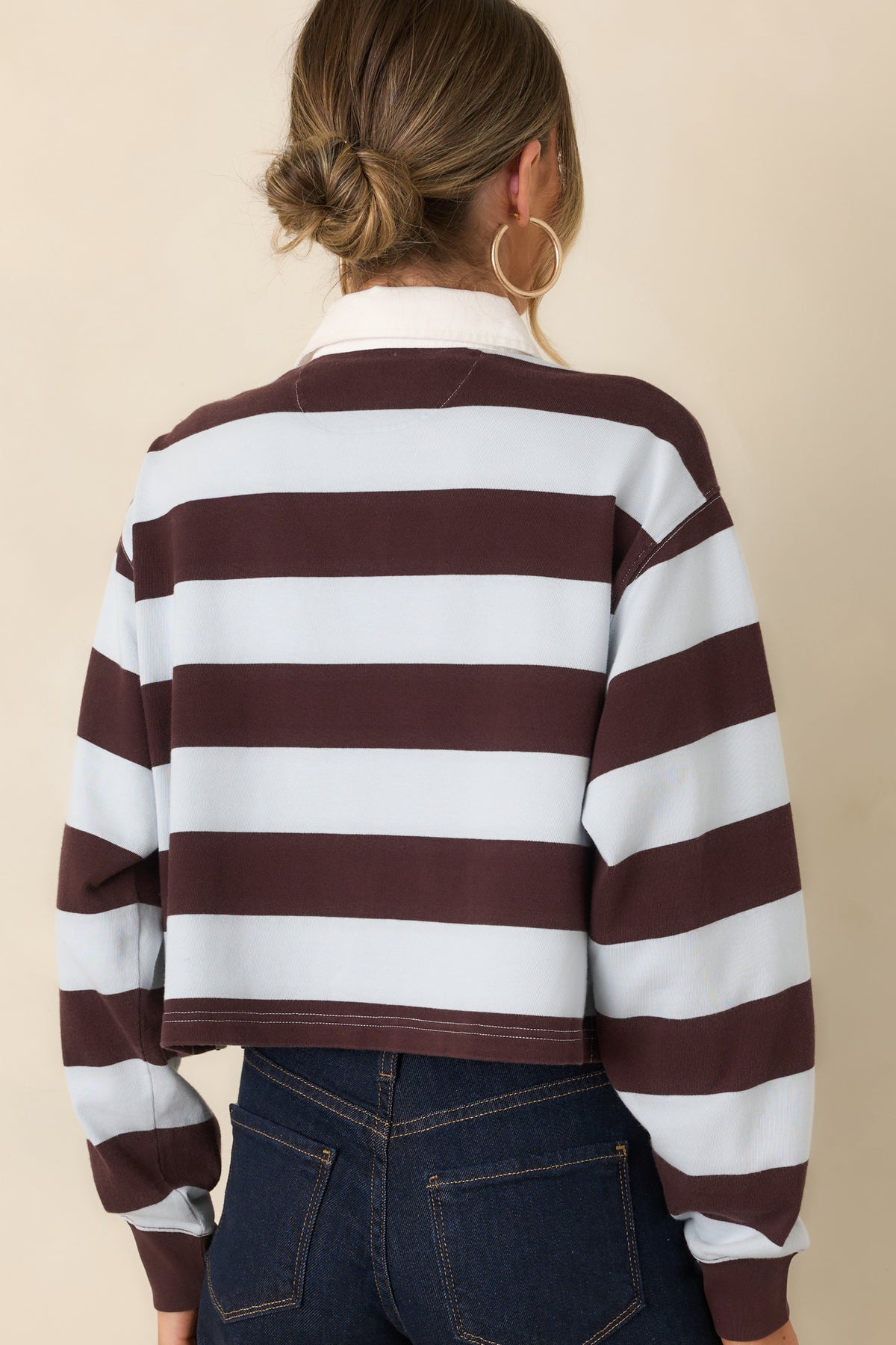 Rear of the striped rugby top showing the horizontal stripe pattern, long sleeves, and straight hem.