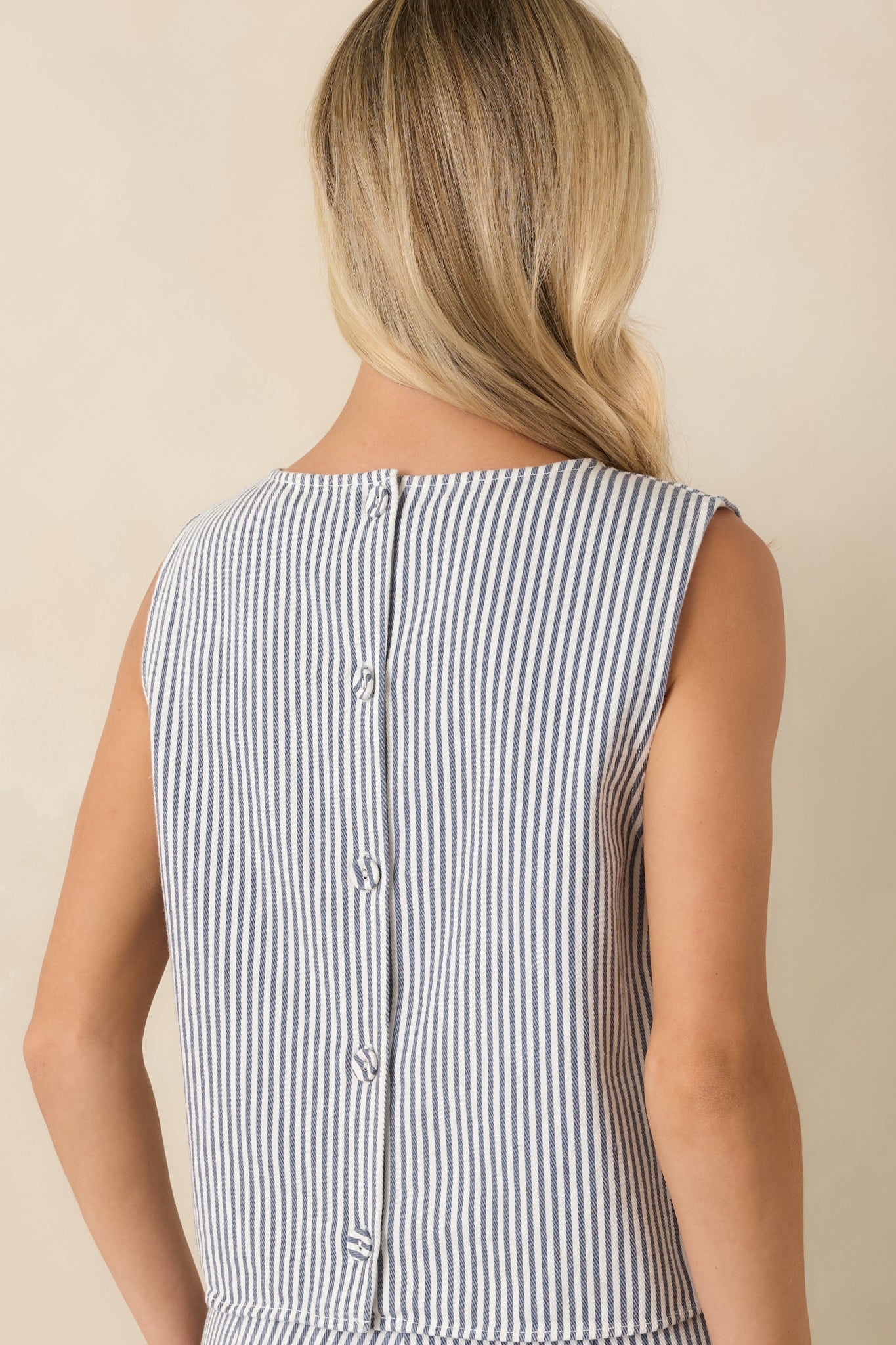 Back view of the striped top featuring a full row of functional buttons and a relaxed boxy silhouette.