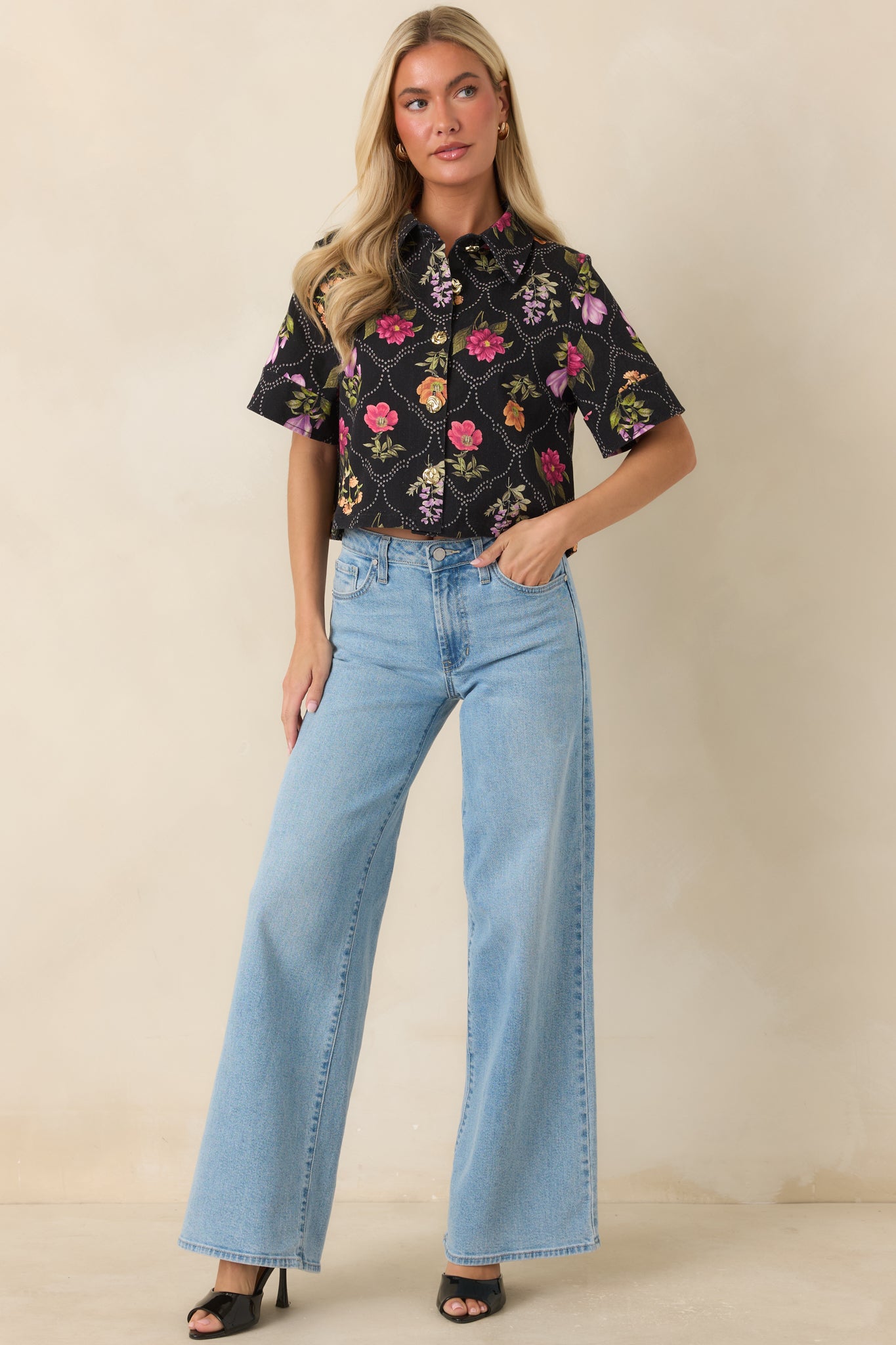 Structured cropped top featuring a black backdrop, multicolored floral print, and a polished button-front design.