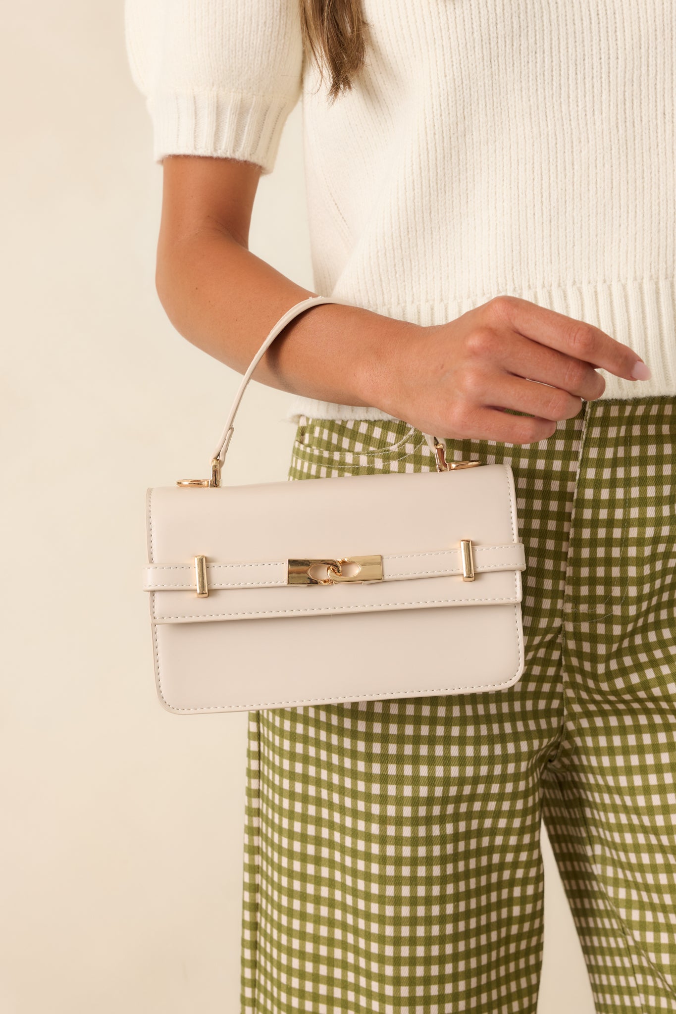 Structured faux leather handbag featuring a classic silhouette, gold-tone hardware, front belt detail, and top handle.