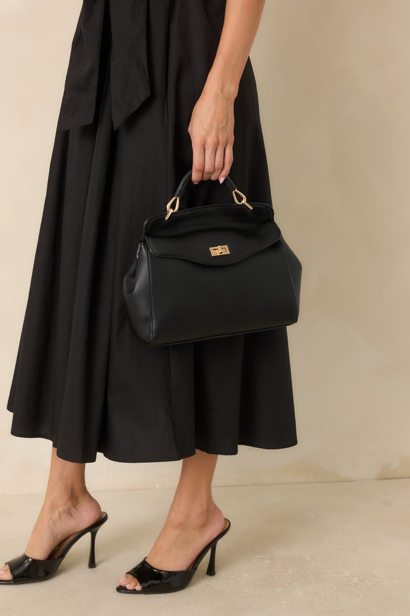 Structured faux leather handbag with a rounded shape, spacious interior, polished gold-tone hardware, and versatile carrying options.