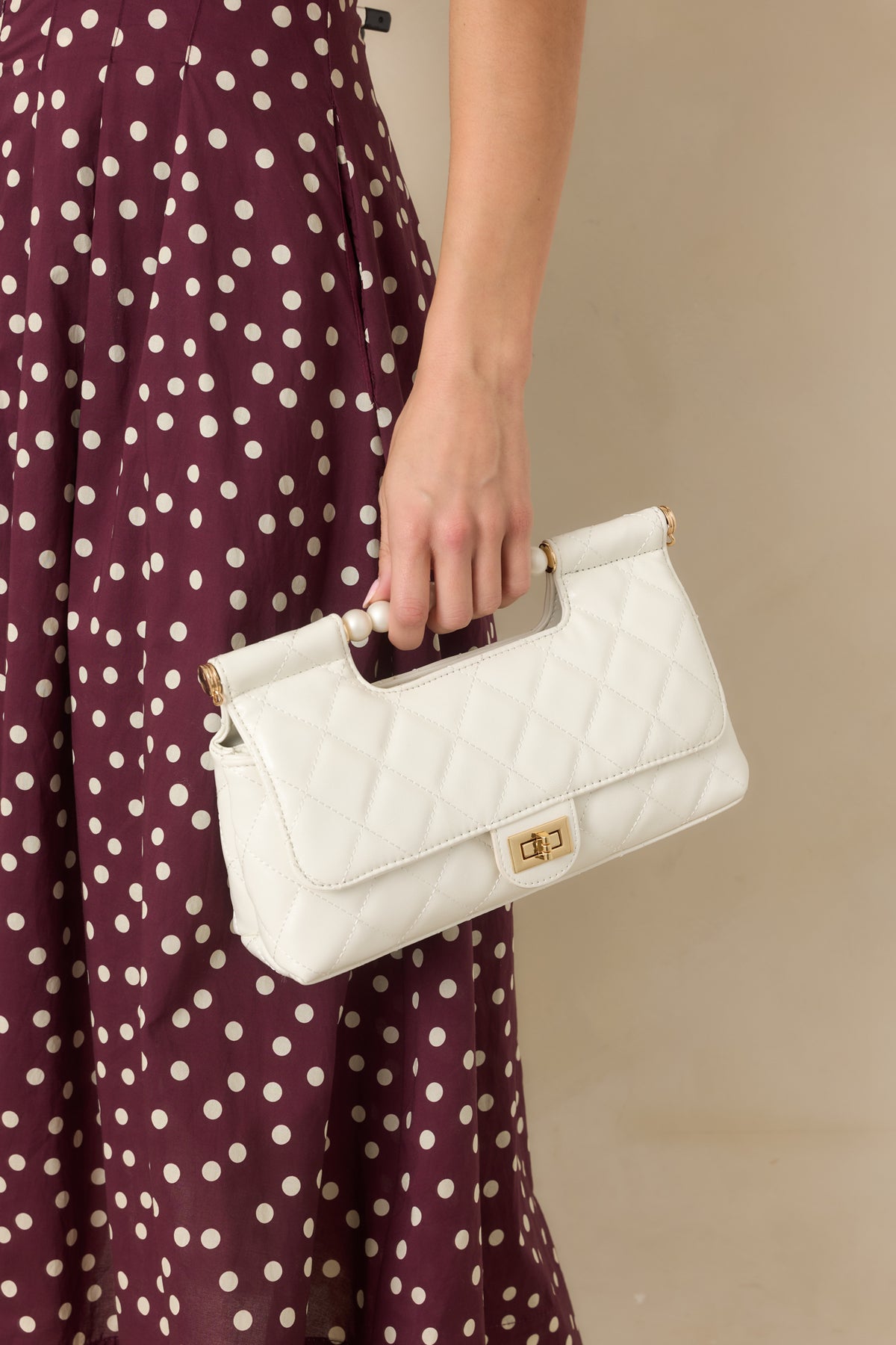 Structured handbag featuring a gold-tone turn lock closure and optional shoulder strap.