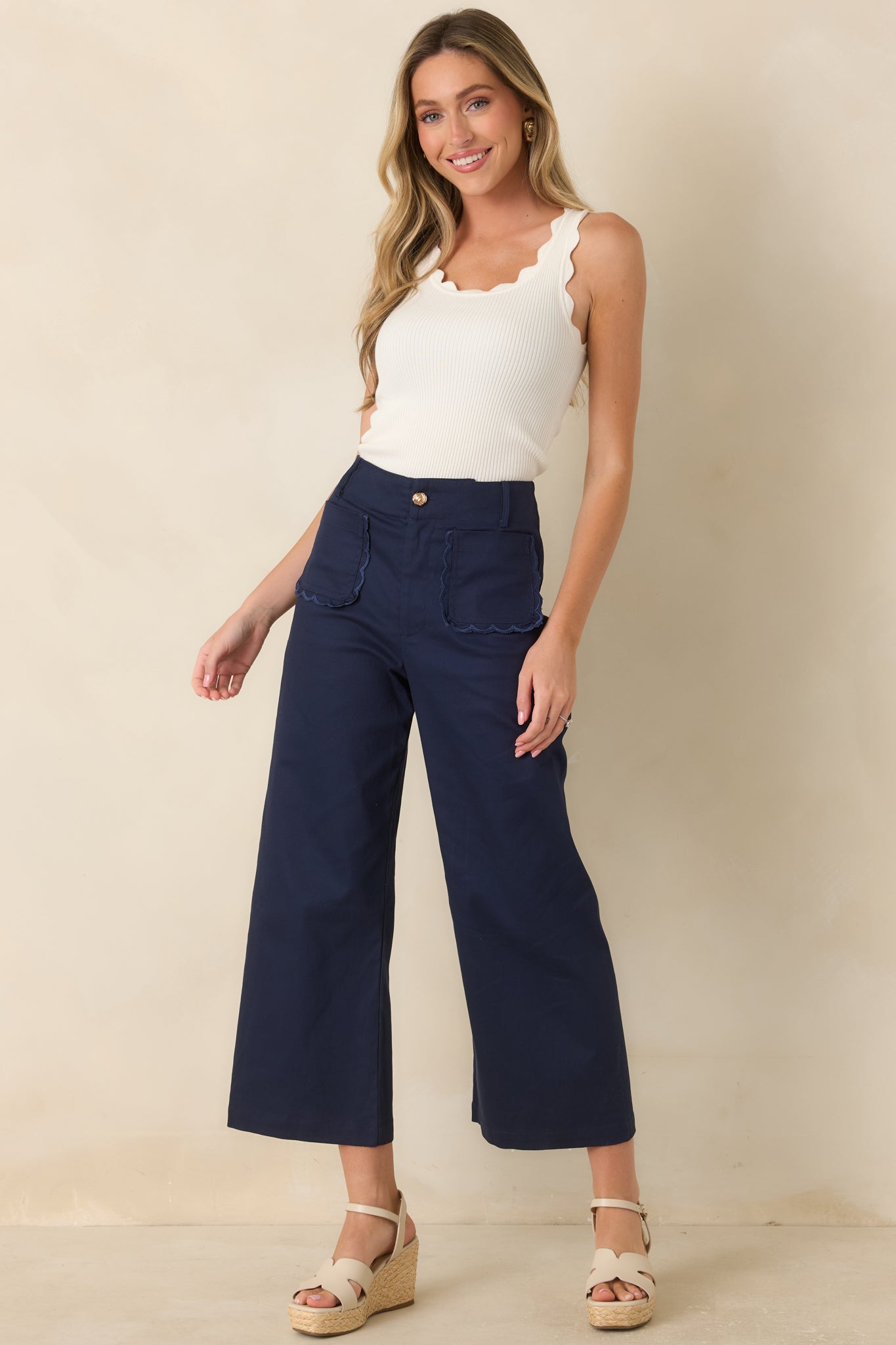 High-waisted wide-leg pants featuring structured fabric, cropped hems, and decorative scalloped pocket detailing.