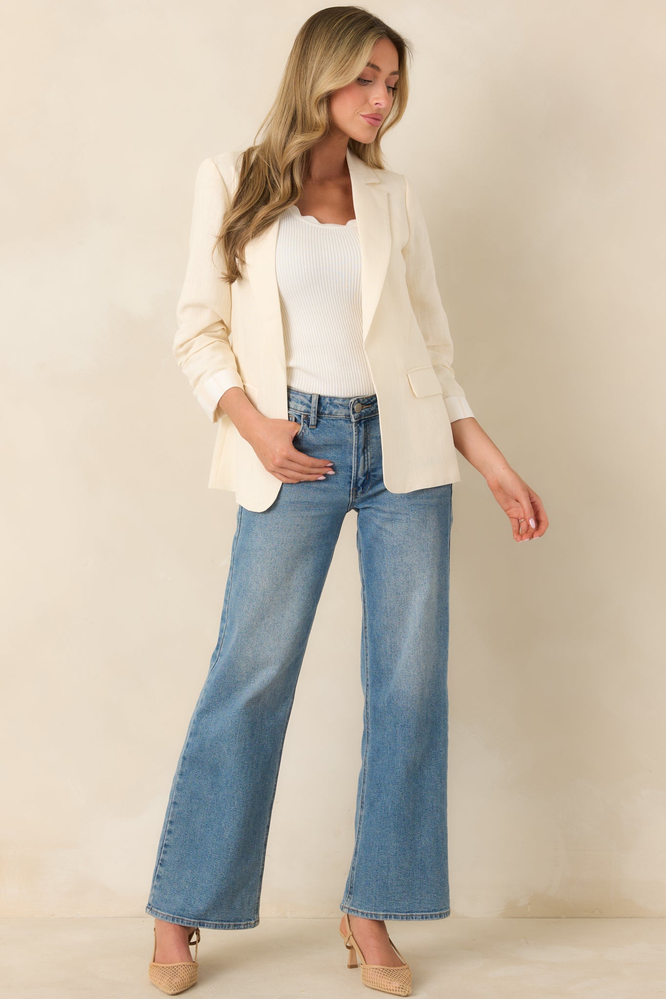 Structured ivory blazer featuring tailored lapels and softly ruched three-quarter sleeves along a clean, elongated shape.