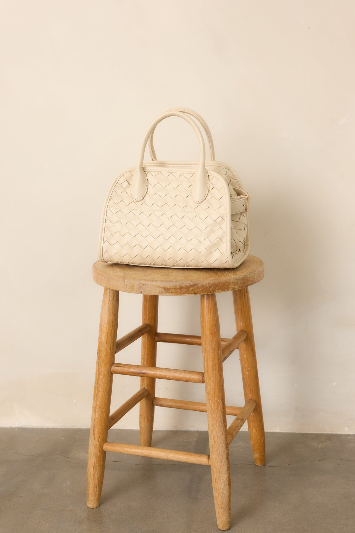 Close view of the structured handbag highlighting the magnetic flap closure and smooth top handle construction.