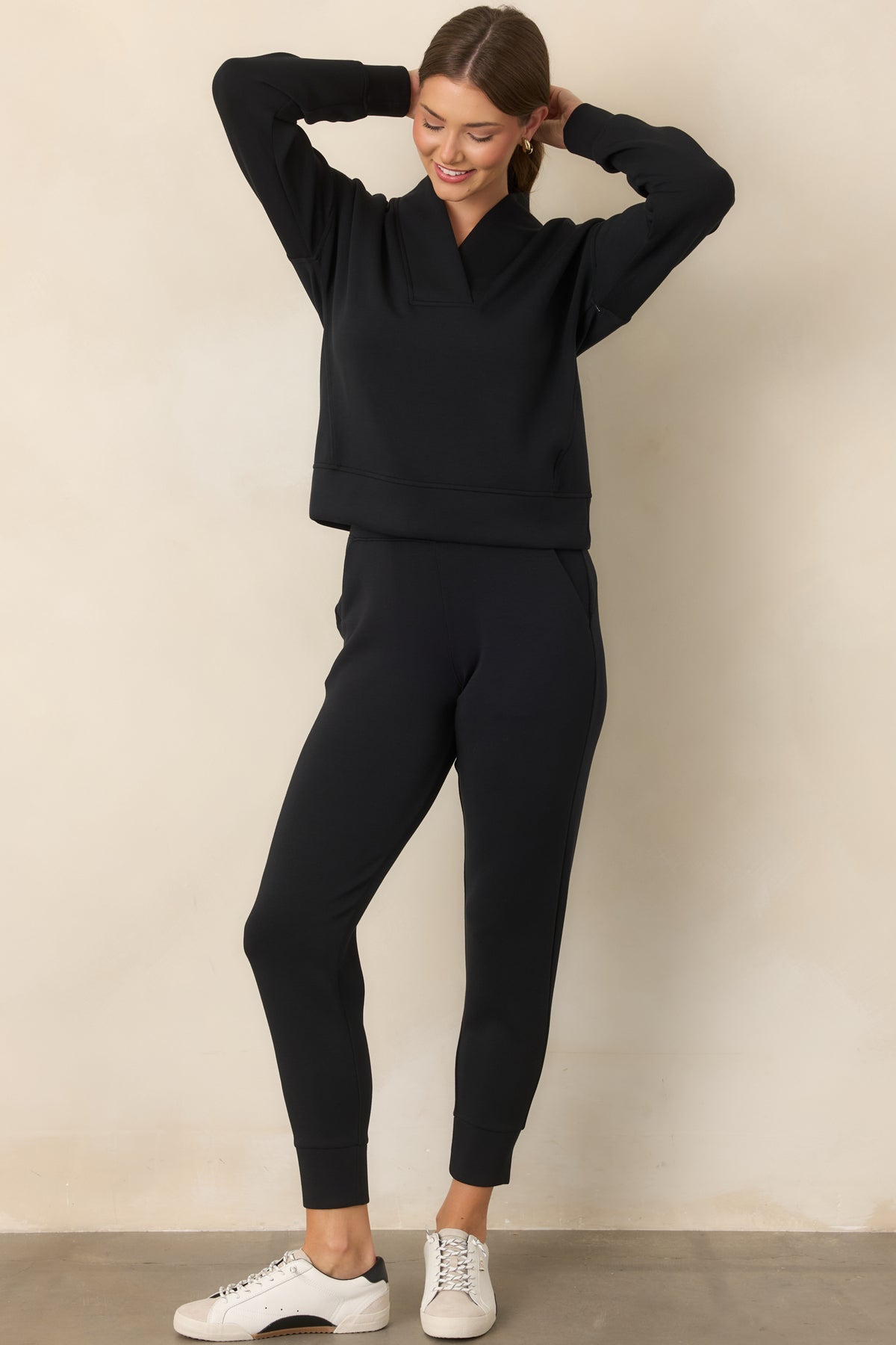 Structured top featuring a wide collar, V-neckline, dropped shoulders, long sleeves, and banded cuffs.