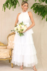 Front view of this dress that features a high neckline with ruffle detailing, a button closure at the back of the neck with a keyhole cutout, a zipper in the back, and a long tiered skirt.