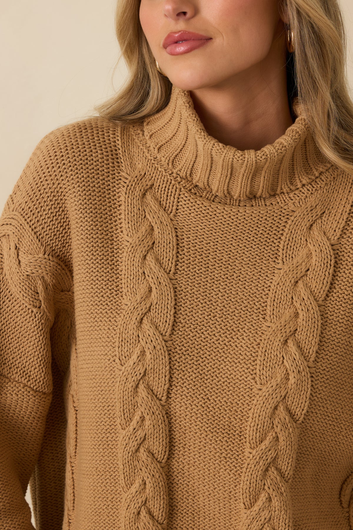 Close-up detail of the sweater showing the chunky cable knit texture and wide ribbed turtleneck.