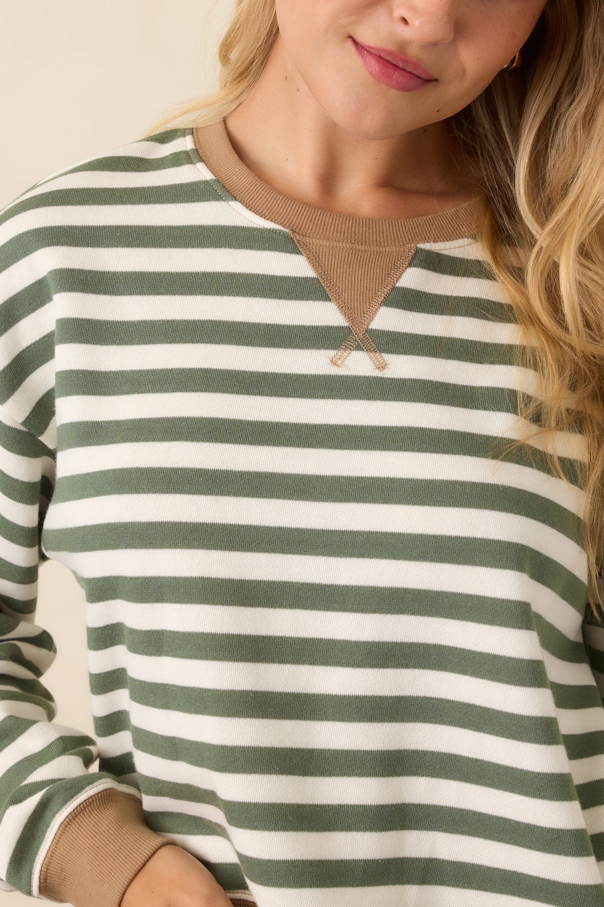 Close-up of the sweatshirt showing the stitched triangular insert and camel ribbed trim.