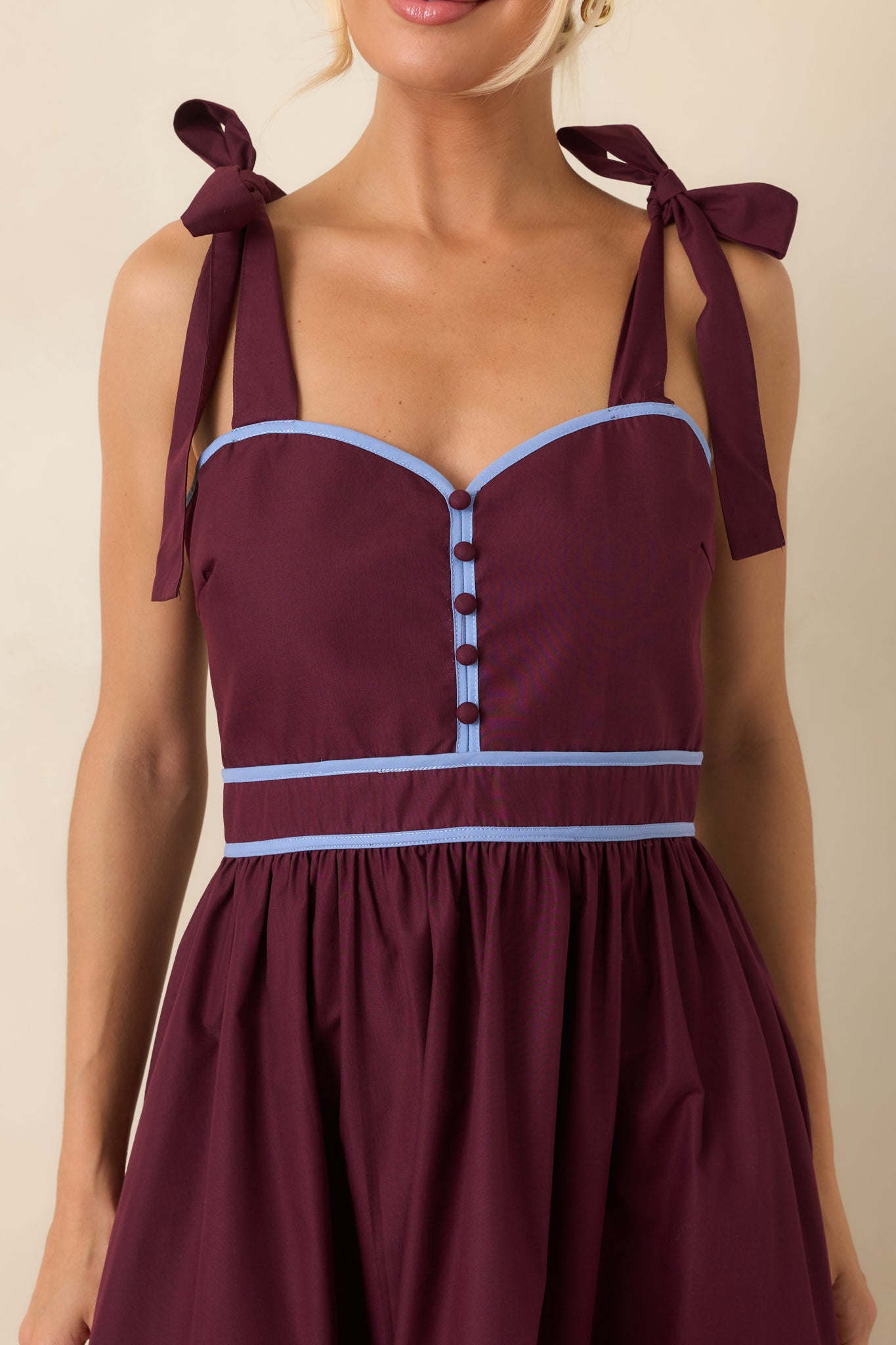 Close-up of the midi dress highlighting the sweetheart neckline, contrast piping, decorative buttons, and soft fabric details.