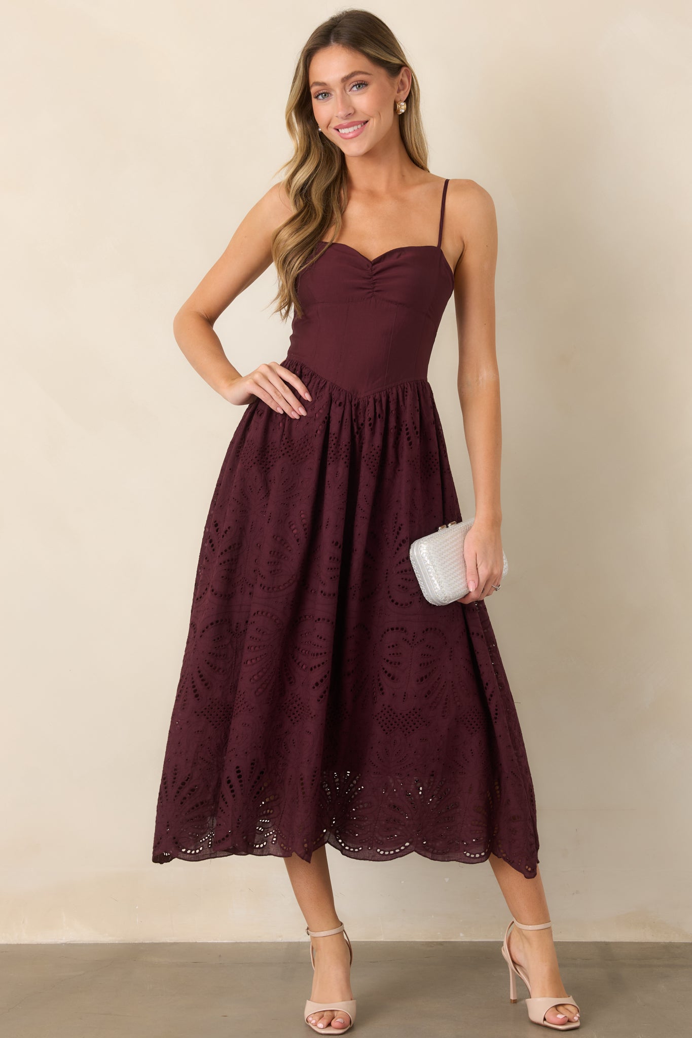 Fitted dress featuring a sweetheart neckline, softly ruched bust, adjustable straps, and a gathered eyelet skirt with a flared silhouette and scalloped hem.