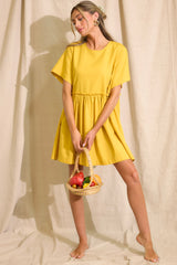 Full body view of this yellow dress featuring a round neckline, short sleeves, ruffle detailing along the waistline, and functional pockets at the hips.