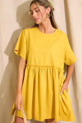 Front view of this dress that features a round neckline, a keyhole cutout at the back of the neck with a button closure, short sleeves, and ruffle detailing along the waistline.