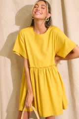 Front view of this dress that features a round neckline, a keyhole cutout at the back of the neck with a button closure, short sleeves, ruffle detailing along the waistline, and functional pockets at the hips.