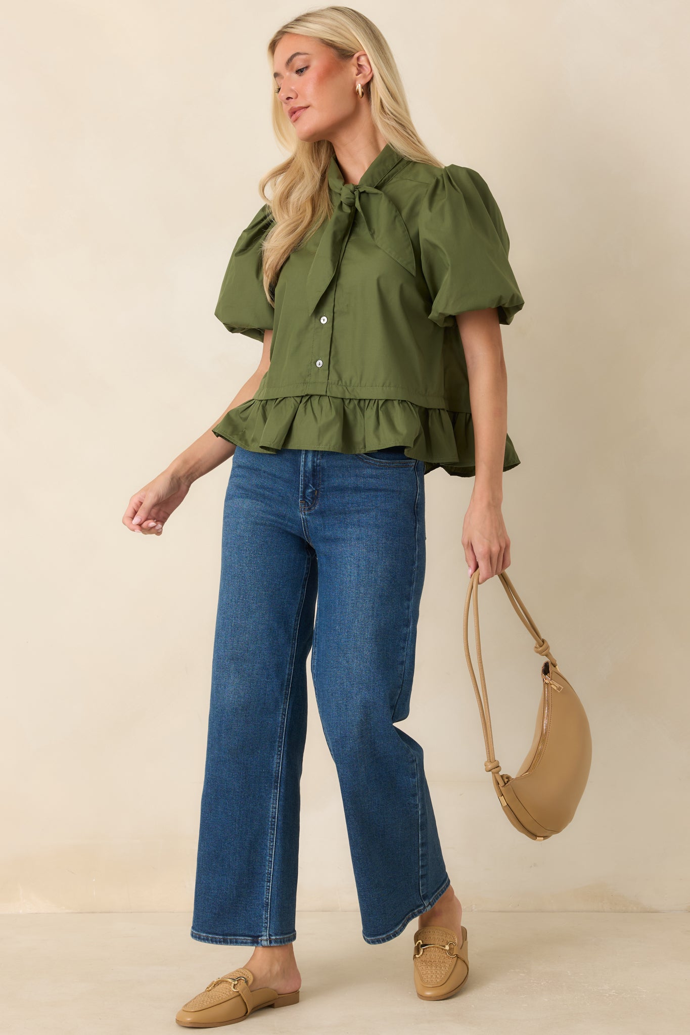 Moss green top showcasing a tailored fit through the bodice with statement sleeves, a feminine bow detail, and a flounced hem.