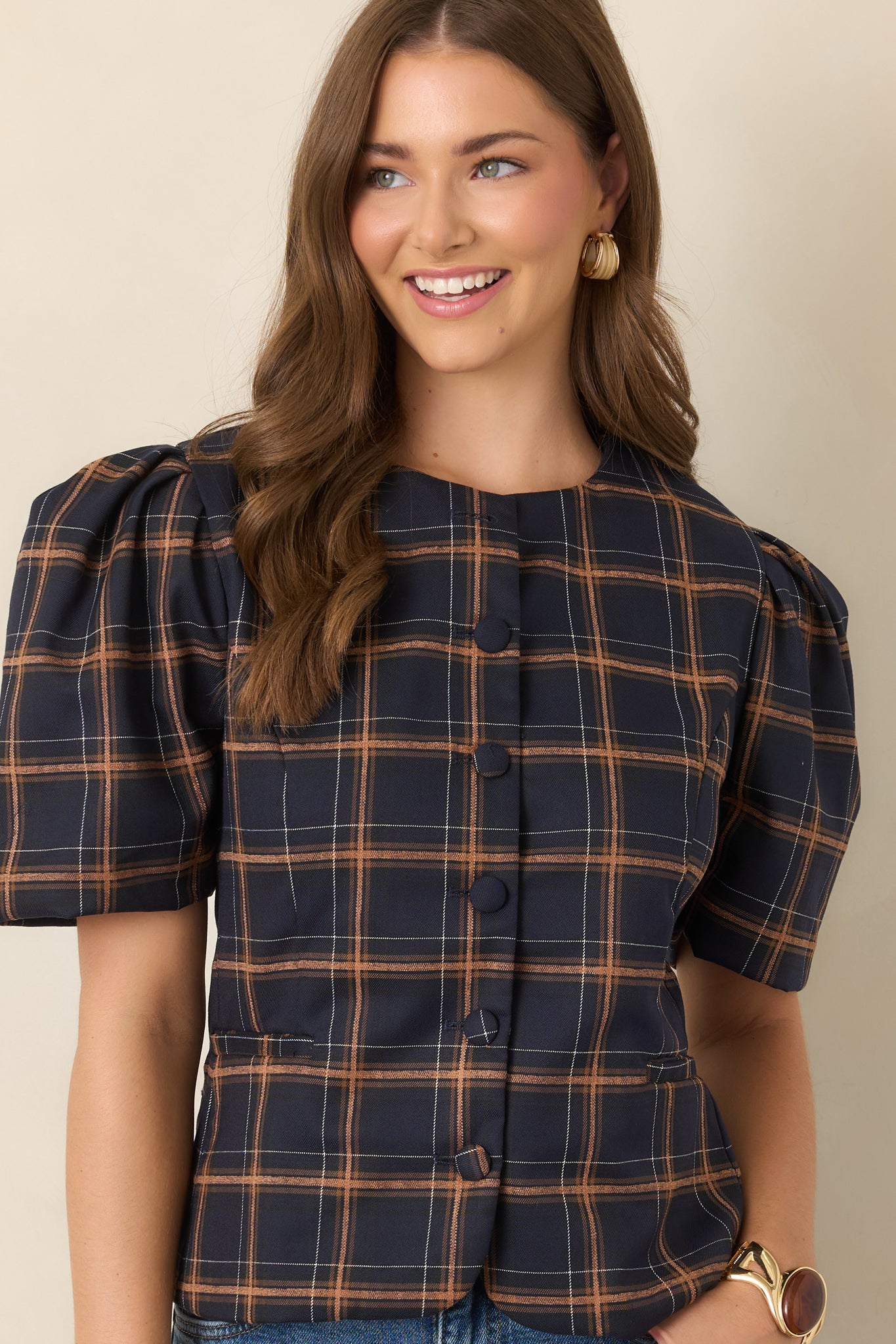 Tailored navy plaid top with contrasting camel and ivory checks, sculpted seams, a cinched waist, voluminous elbow-length sleeves, and a neat row of covered buttons.