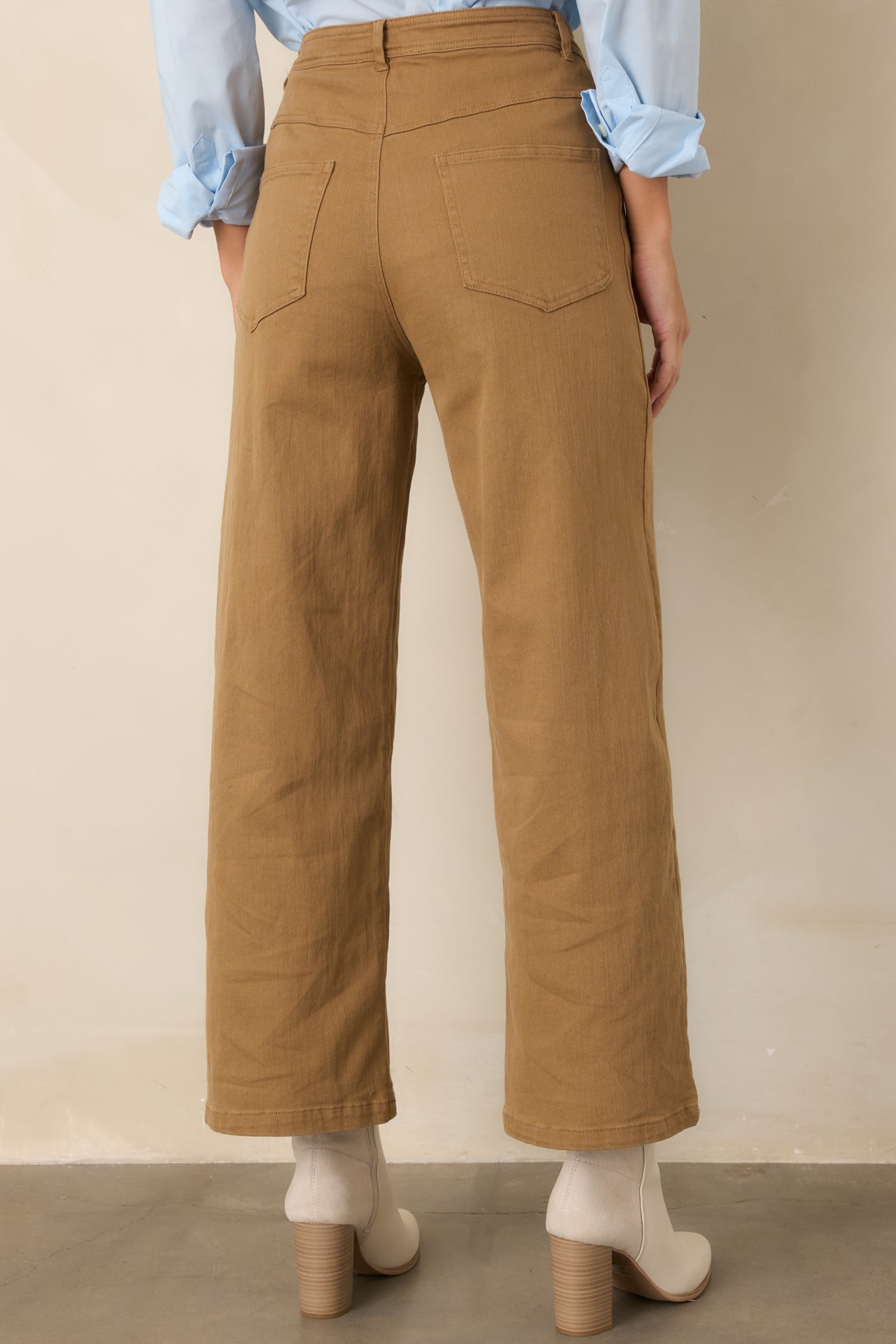 Rear of the warm tan pants showing the back patch pockets and cropped wide-leg silhouette.
