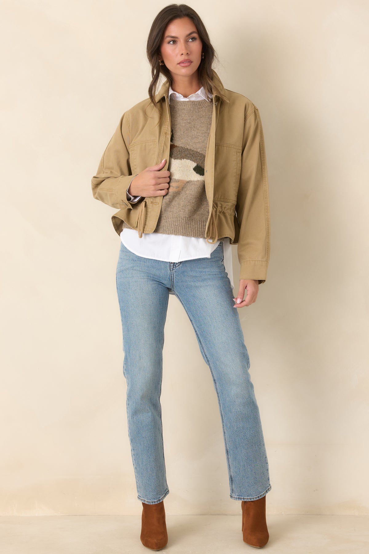 Sturdy tan jacket features a button-front design, long sleeves, and a relaxed silhouette with an adjustable hem.
