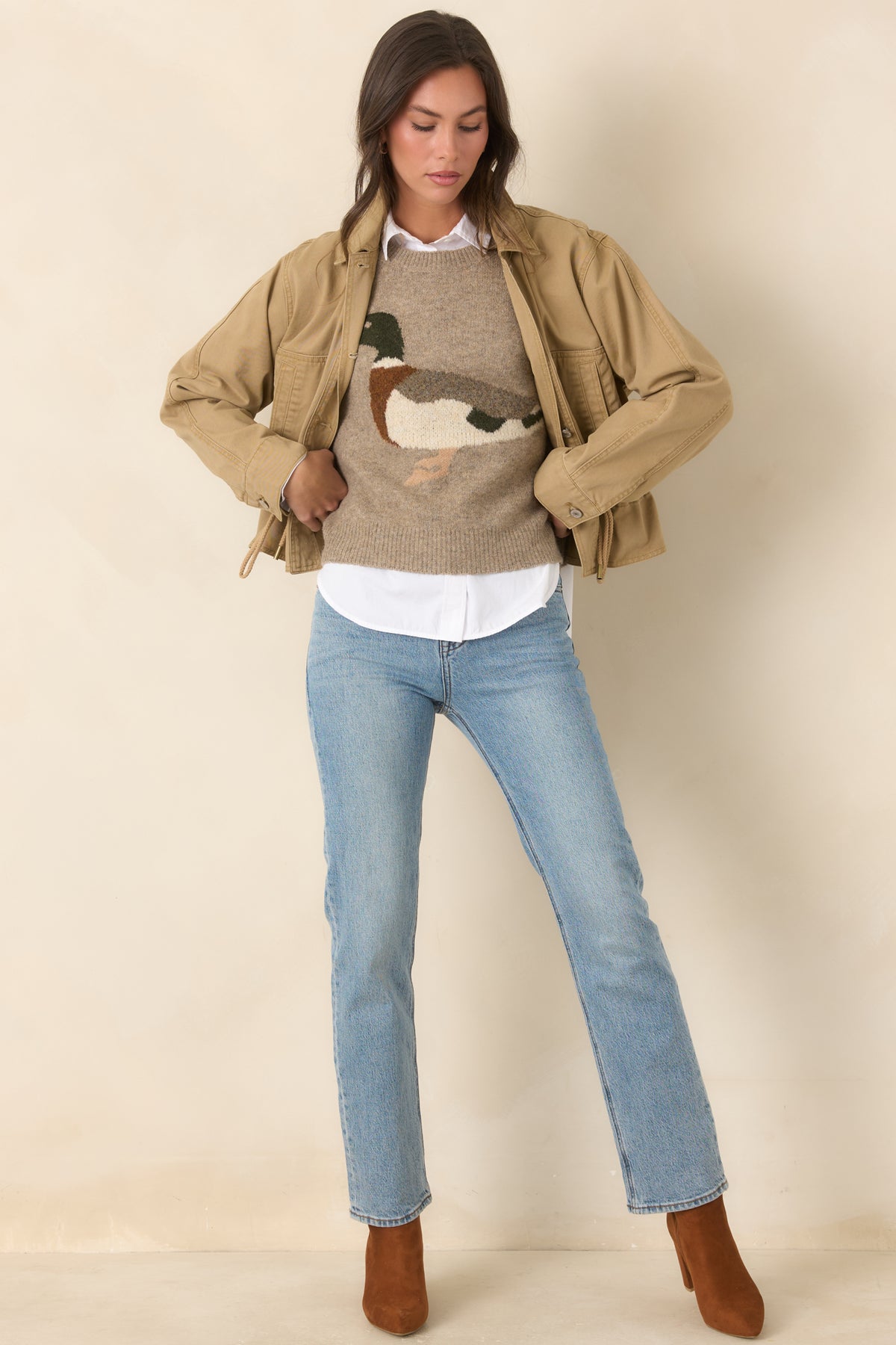 Collared tan utility jacket features practical front pockets, buttoned sleeve cuffs, and a softly gathered hem.