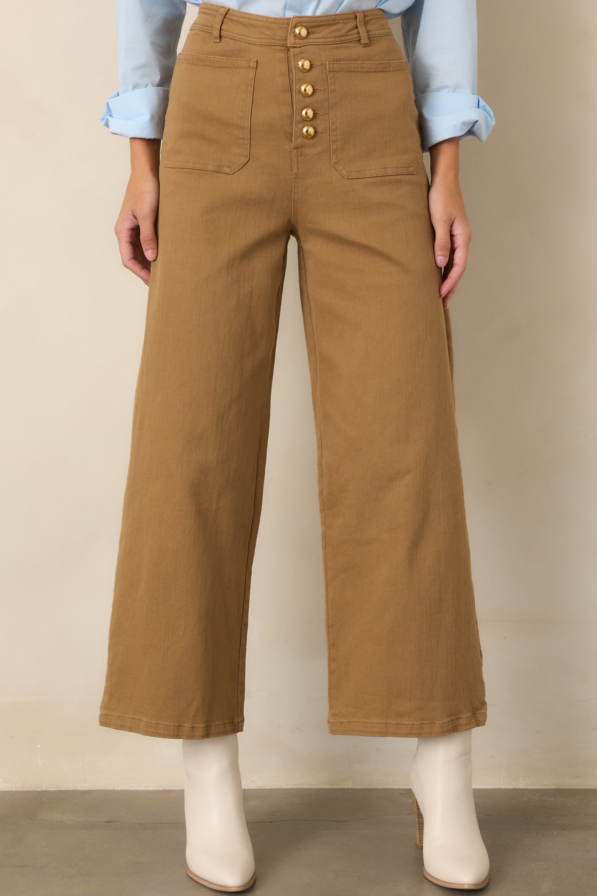 Tan cropped pants highlighting the front patch pockets, gold-tone button row, and stretch cotton fabric.
