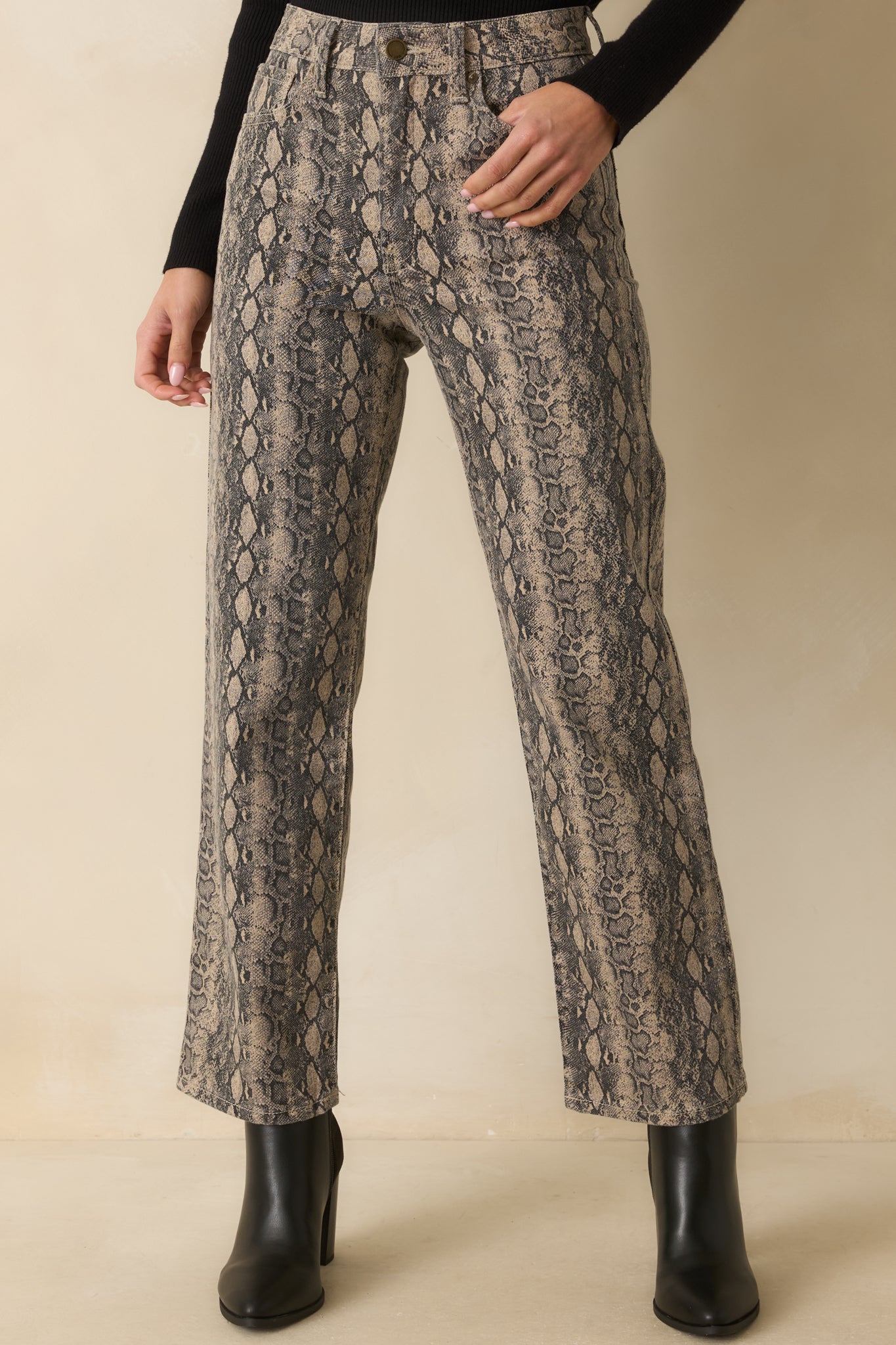 Close view of the high-rise waist and belt loops on the tan and gray snakeskin jeans.