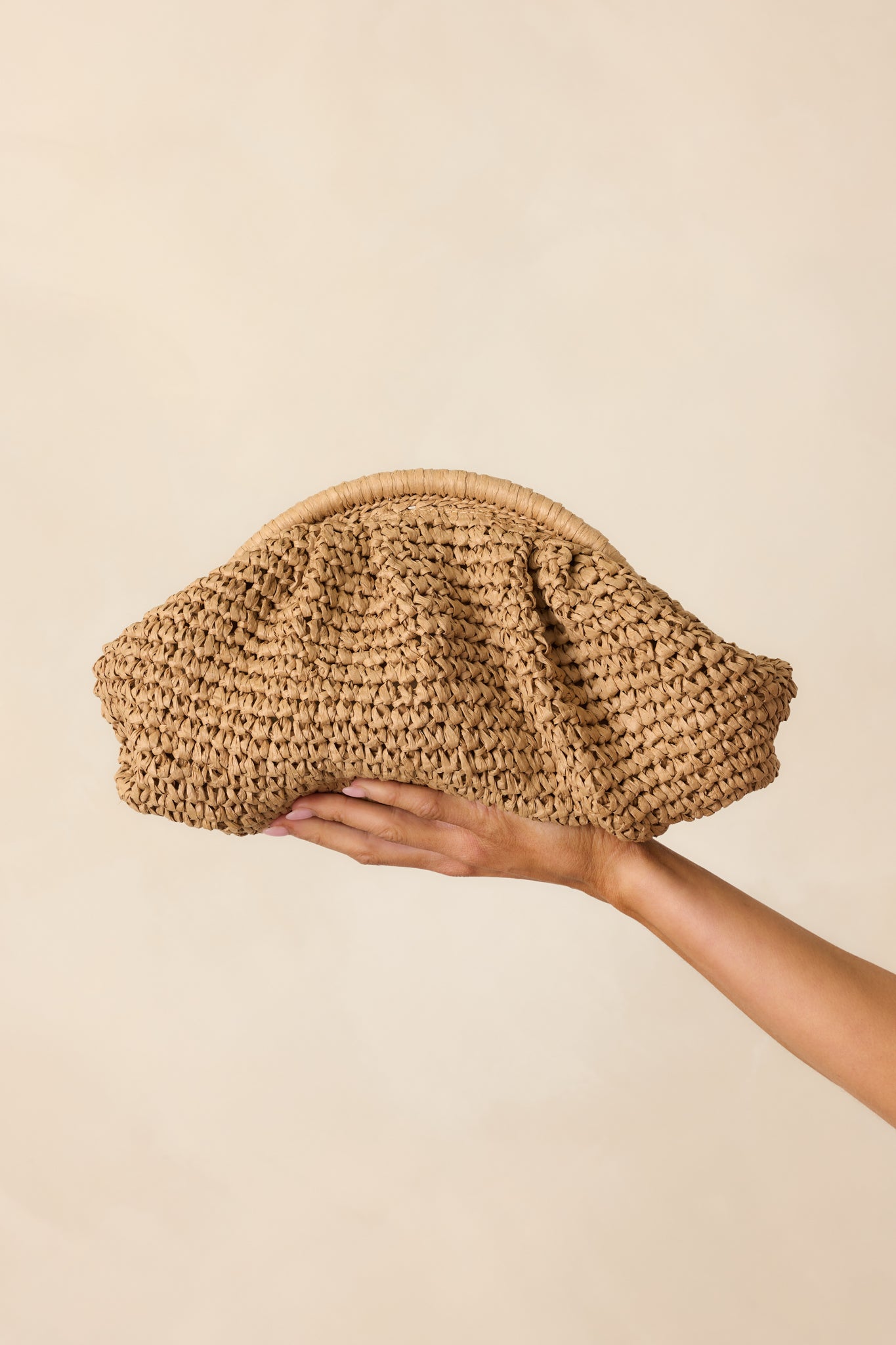 Cropped view focusing on the ruched texture of the tan raffia material and the bag’s soft, slouchy structure.
