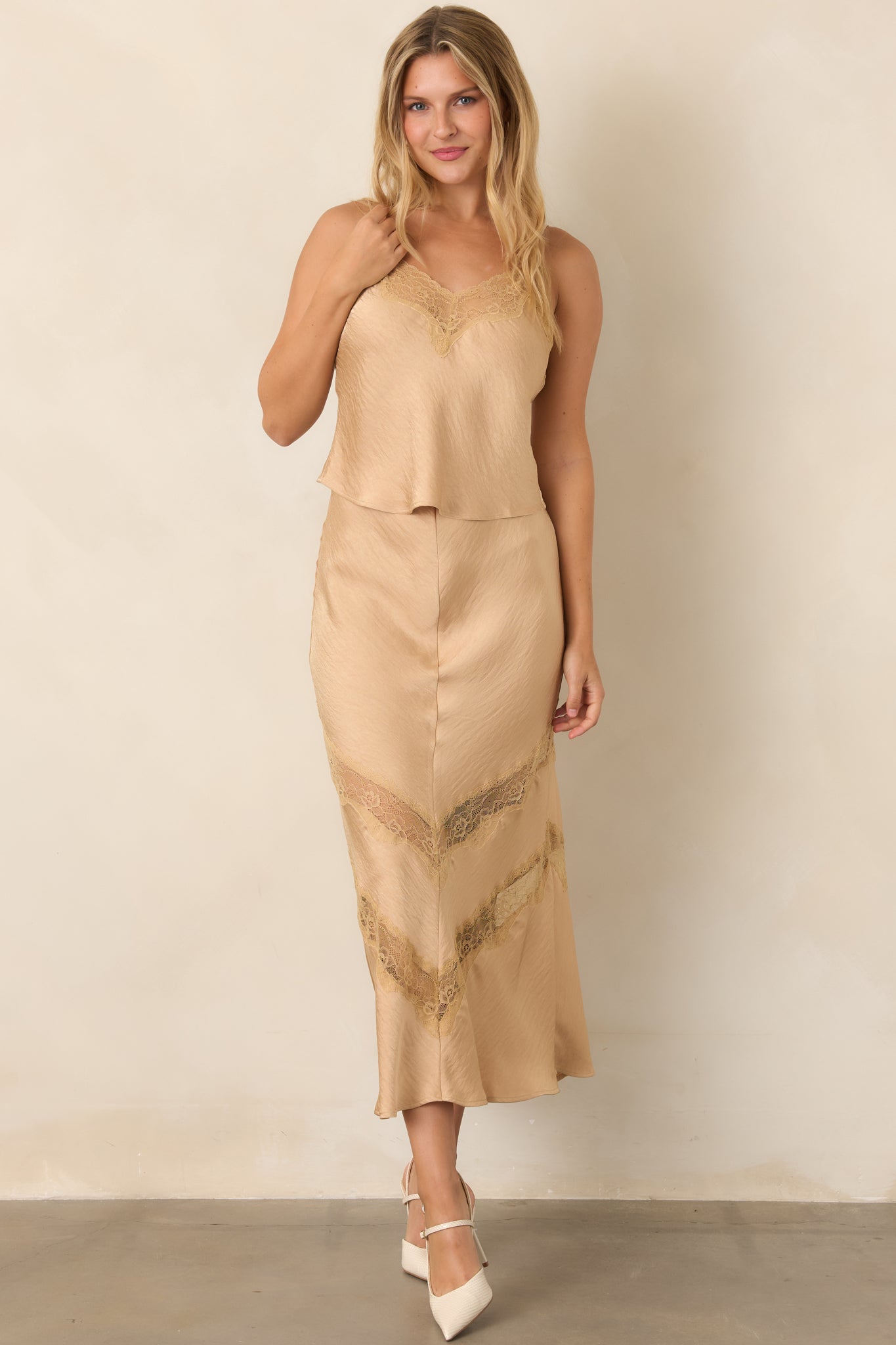 Warm tan top featuring slender adjustable straps, a V-neckline, delicate lace trim, and a relaxed draped shape.
