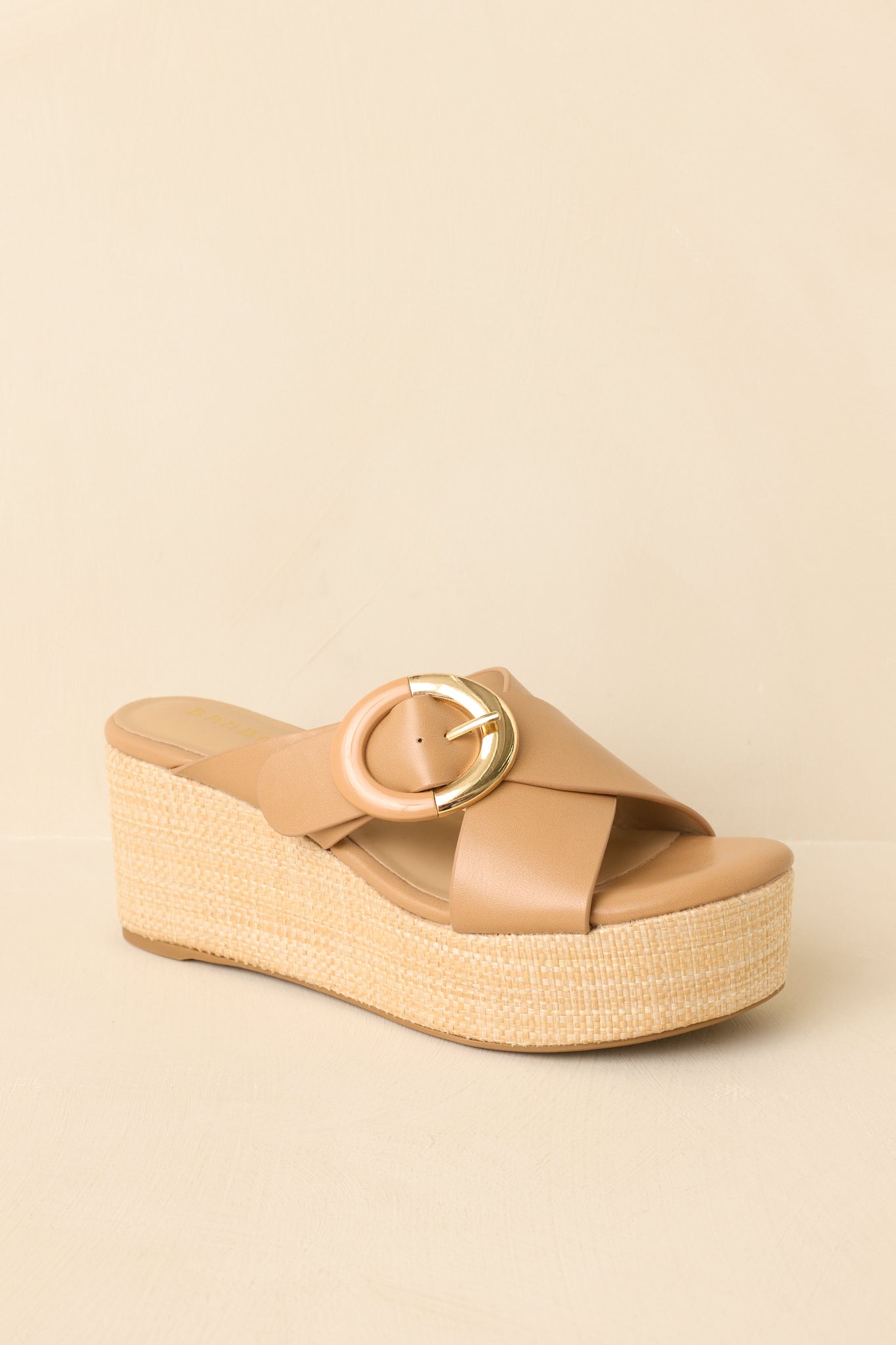 Cropped view of tan slip-on wedge sandals featuring a smooth faux leather upper and textured platform sole.